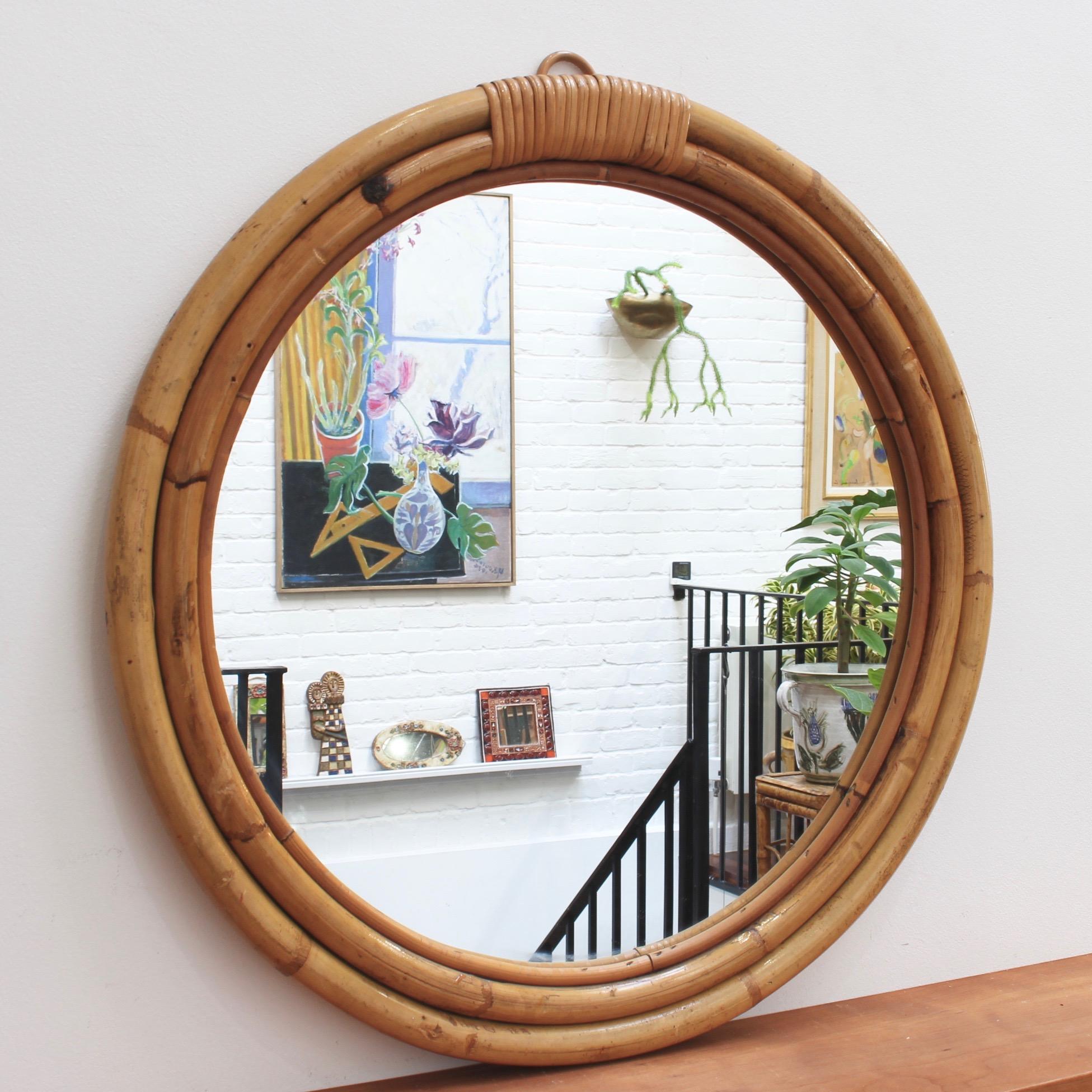 Italian 'porthole' style bamboo and rattan wall mirror circa 1960s. Three concentric tubular rounds of both bamboo and rattan form the structural frame for this porthole mirror with bands of binding rattan. There is a graceful, aged patina on the
