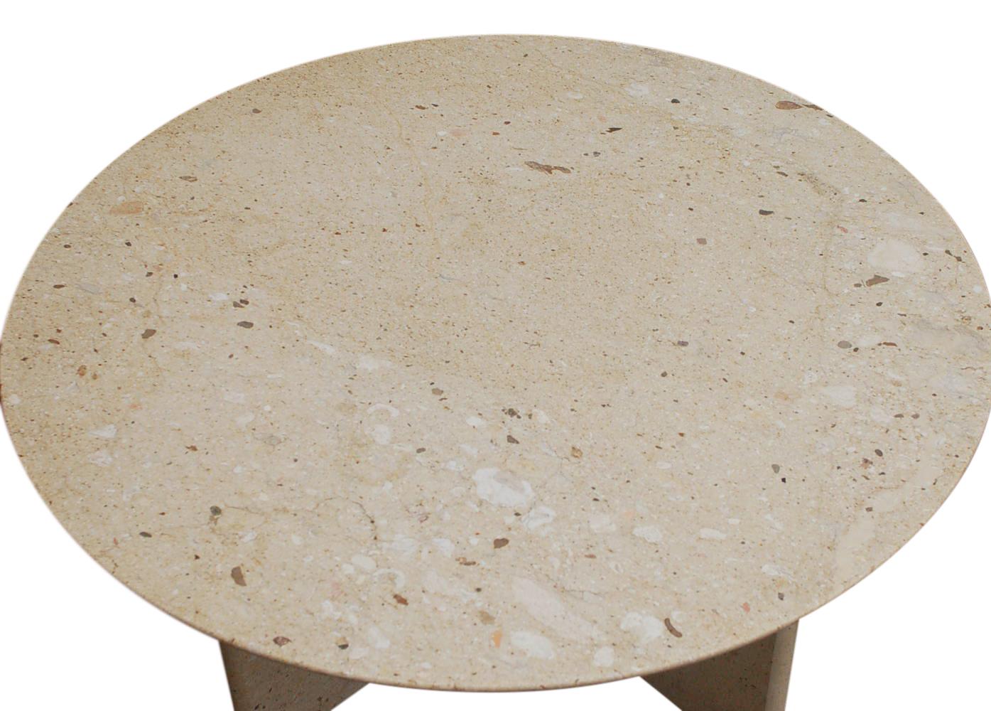 A sleek modern round cocktail table made in Italy in the 1980's. It features a beige colored slab marble with an X base and chrome ring accent.