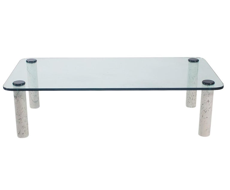 A large and substantial coffee table from Italy circa 1970's. It features a thick clear glass top with chunky solid marble marble legs in white with grey veining.