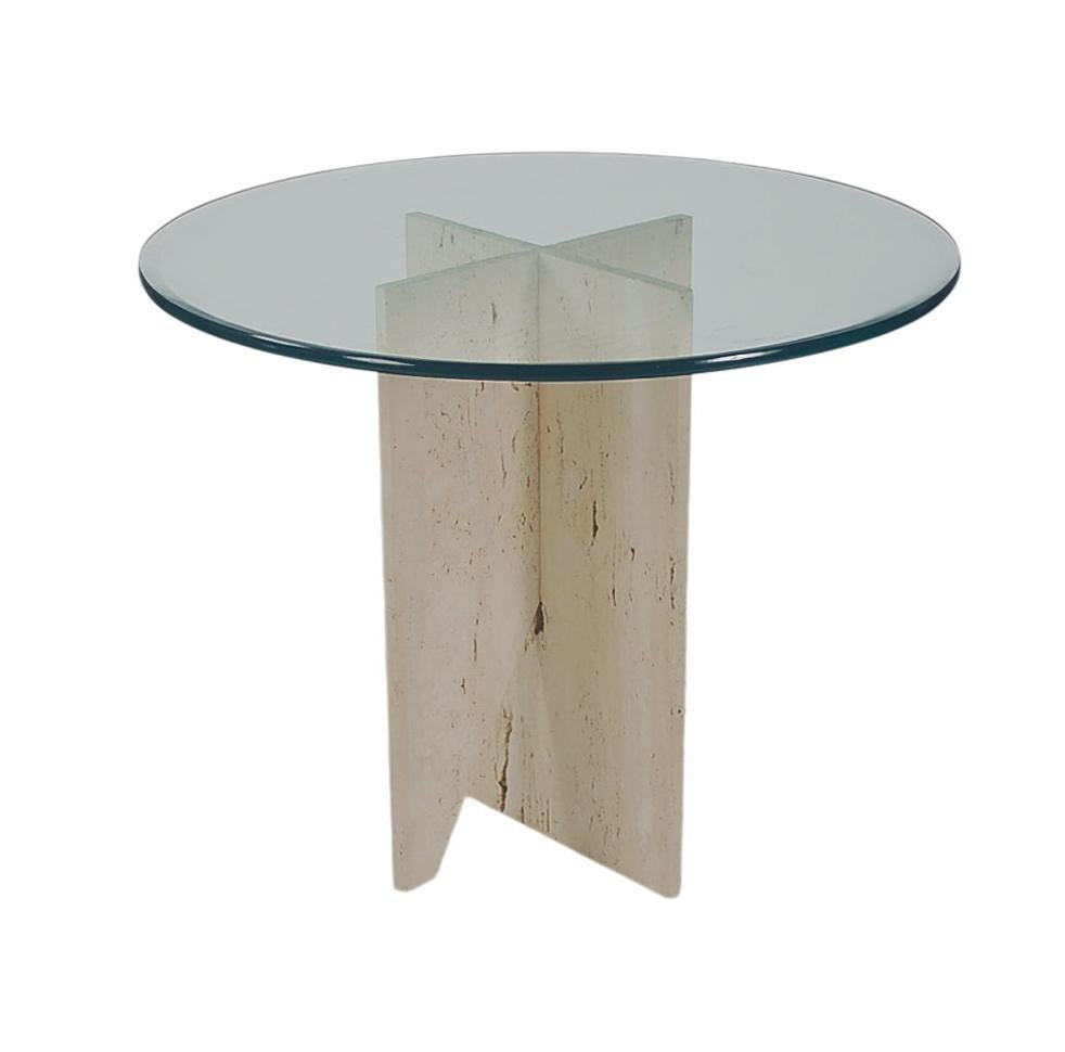 Un bellissimo tavolo da pranzo o centro tavola italiano degli anni '80 circa. Il tavolo presenta una base a X in lastre di travertino con un piano in vetro trasparente di grande spessore.