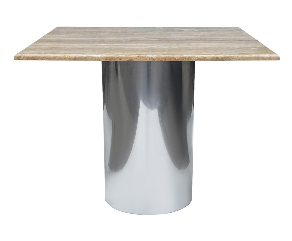 A simple modern Italian travertine dining table ideal for smaller spaces. It features a polished stainless steel base with a travertine slab top. In very good overall condition.