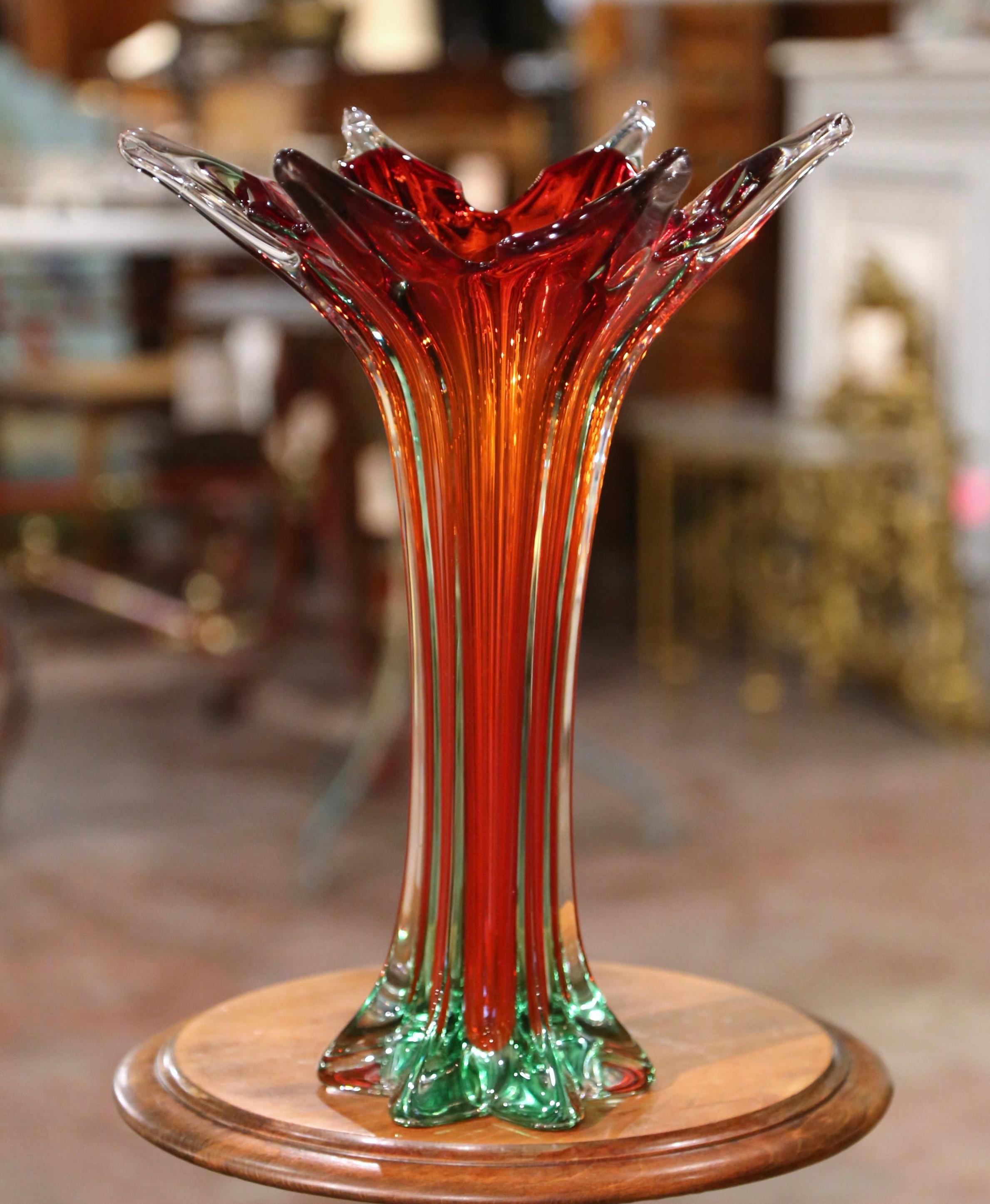 This elegant, hand blown glass console vase was crafted in Italy, circa 1950. The vintage piece attributed to Murano has a cred color center and features a pulled feathered technique with an intricate curl design in red and clear palette. The tall