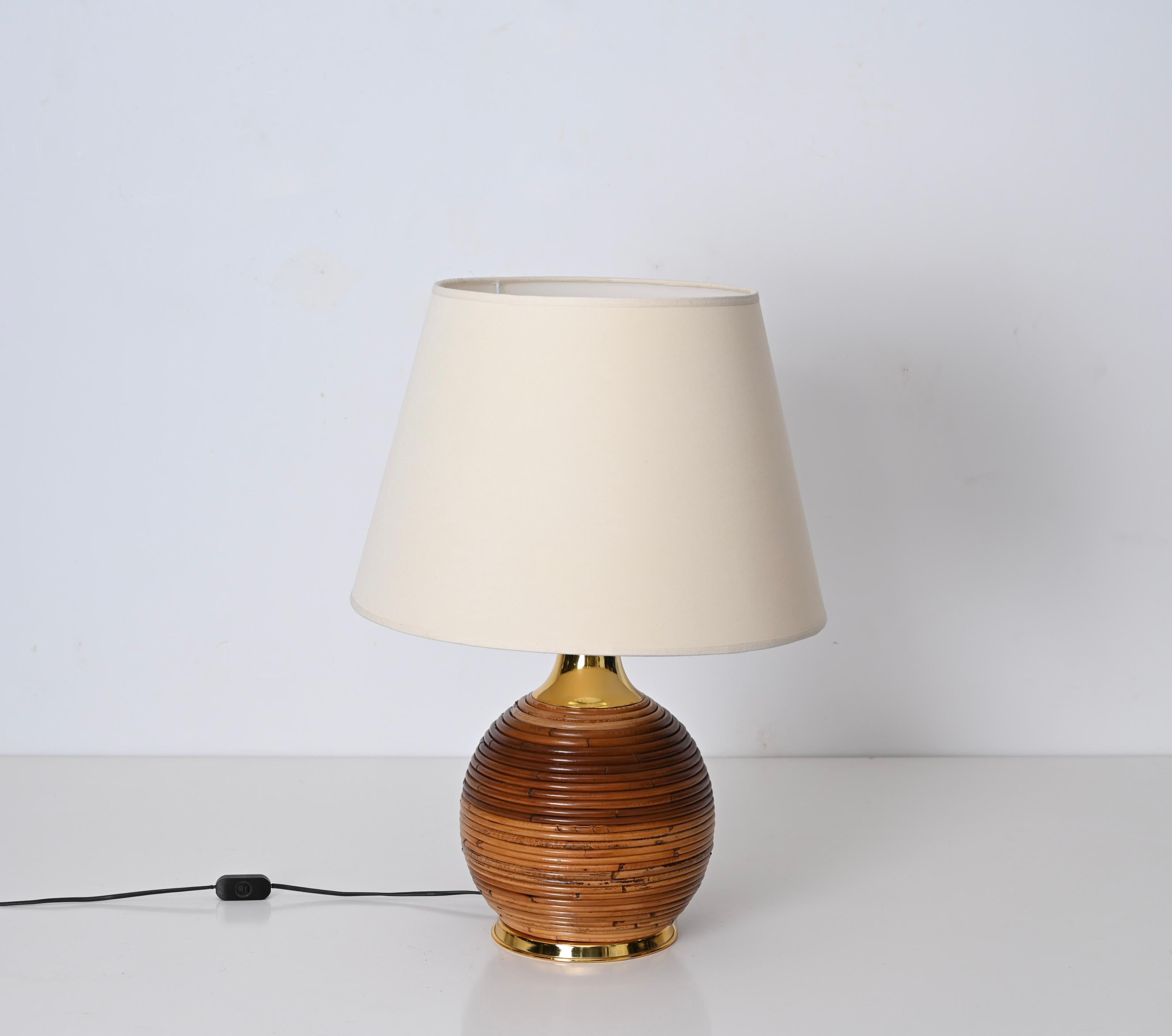 Gorgeous midcentury table lamp in rattan and gilt metal. This fantastic piece was designed by Vivai del Sud in Italy in the 1970s. 

This round lamp features a body made in a beautiful spiral of curved rattan, the base and the neck are in gilt