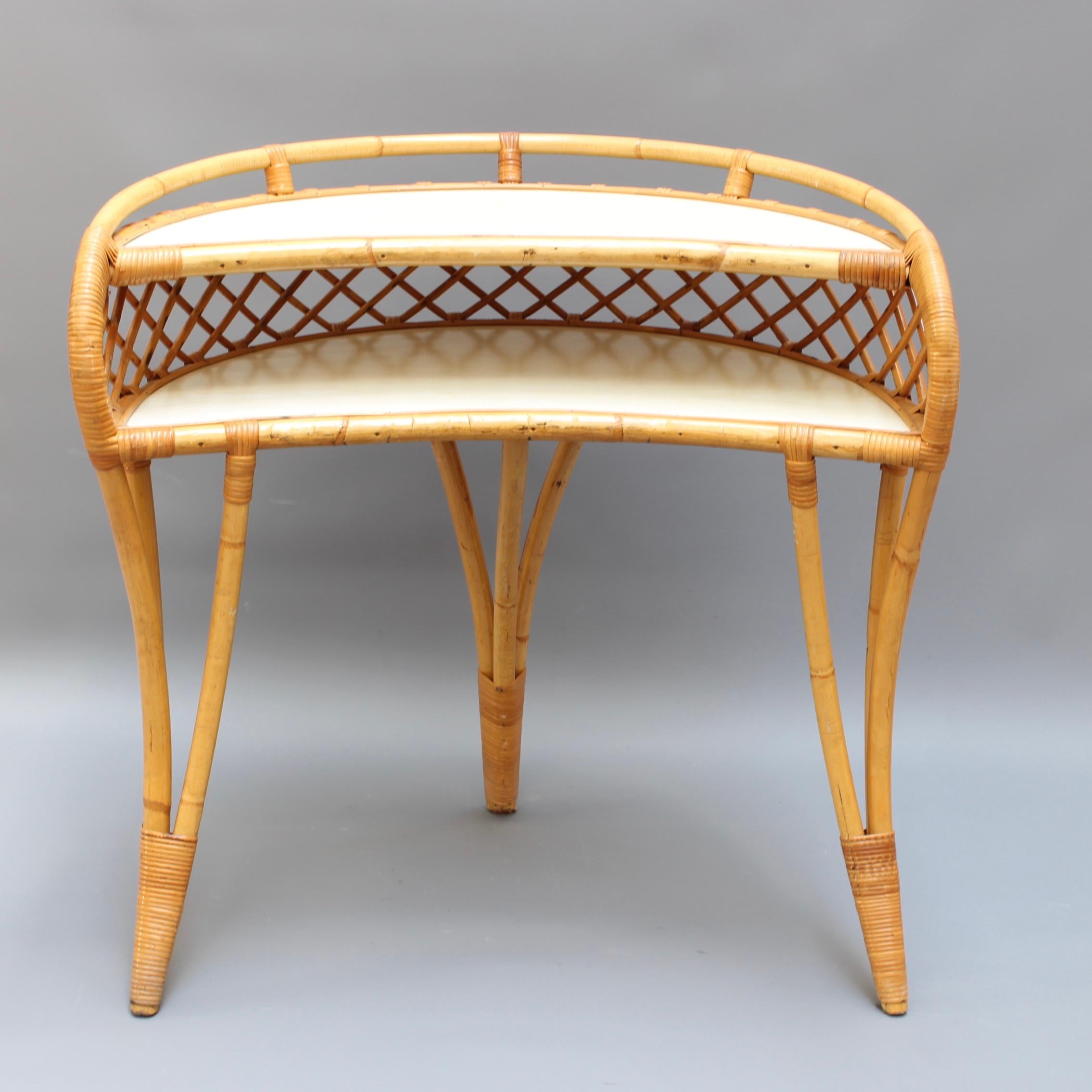 Midcentury Italian rattan desk or vanity table, (circa 1960s). An absolute charmer and stylish piece of the era. There are two horizontal surfaces with a stylishly curved frame and legs. The individual legs are formed from the confluence of three