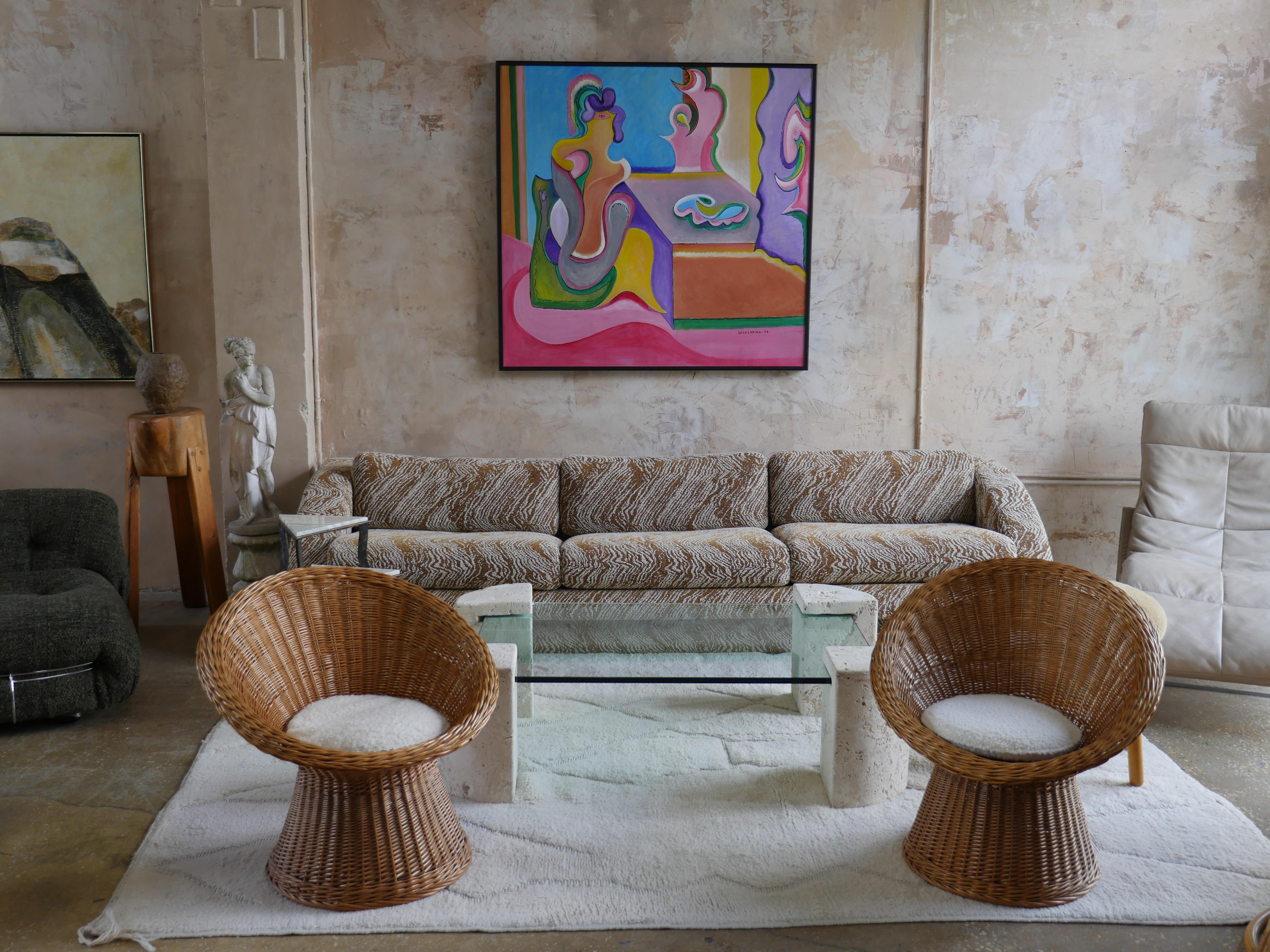 Beautiful pair of Mid-Century rattan, wicker weave lounge chairs with new boucle, off-white colored upholstery from french textile company Les Creations de la Maison. These chairs are elegant statement pieces that add a nice touch of warmth to any