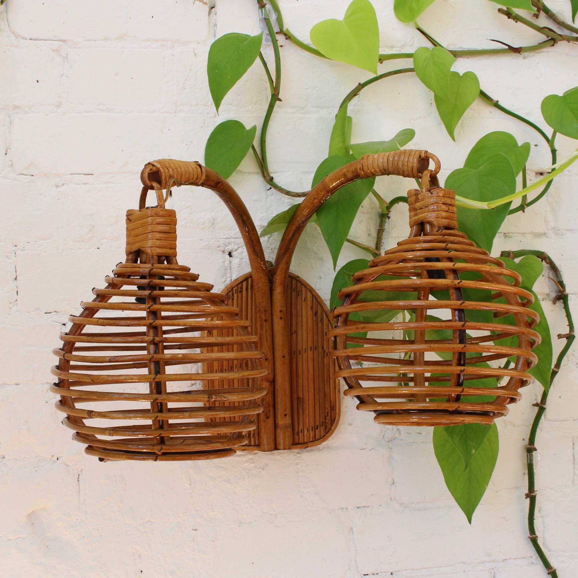 Midcentury Italian rattan wall lights (circa 1960s). Delightfully original, this piece transports you to the Italian Riviera at the height of its glamour. Fixed to the wall with its vertical base, two sensuously curved canes extend outward and