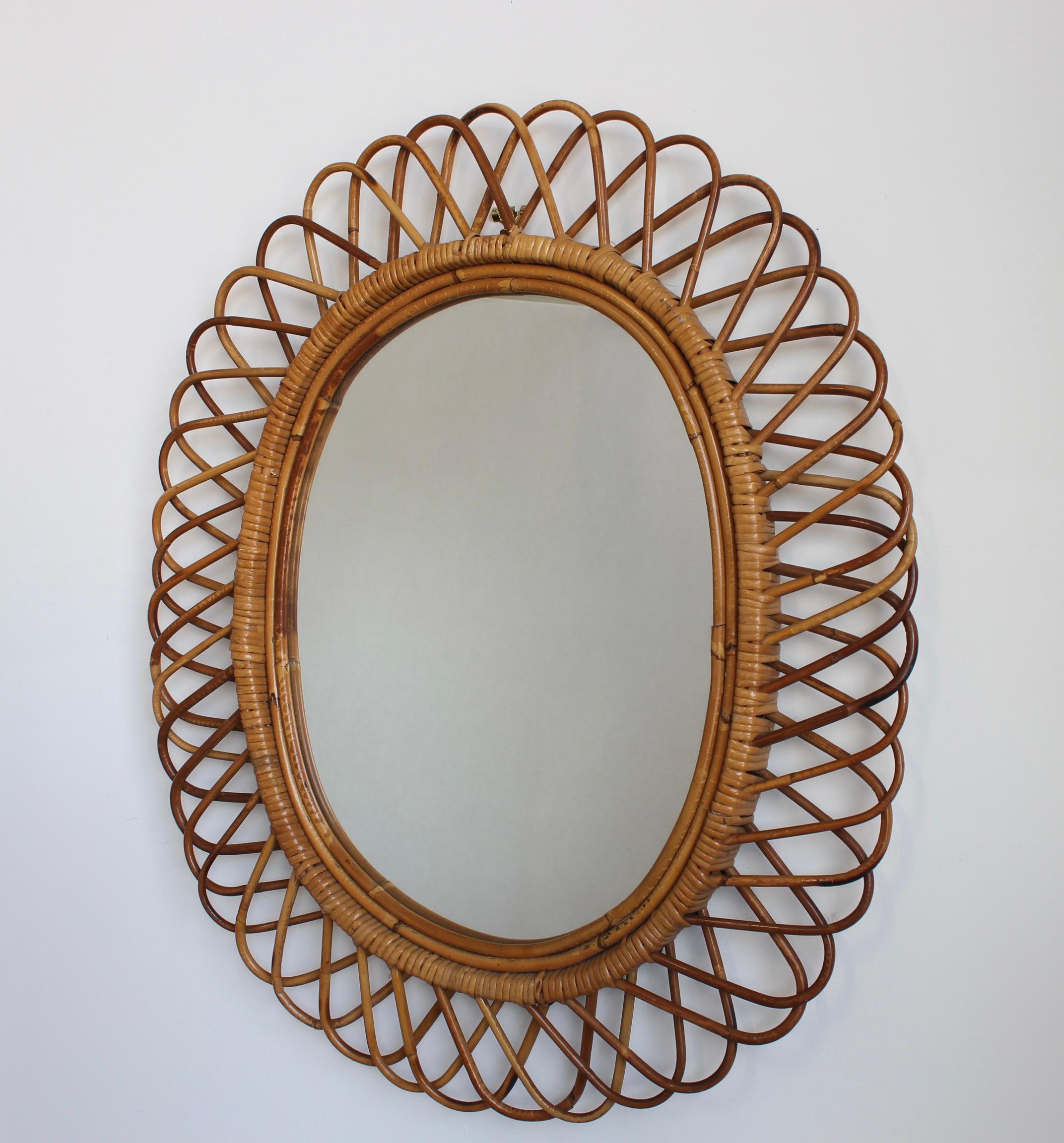 Wandspiegel aus Rattan (ca. 1960er Jahre) in dem unnachahmlichen italienischen Stil, der so beliebt ist. Dieser Spiegel hat ein komplexes Rattan-Geflecht, das sich in einer Reihe von hufeisenförmigen Vorsprüngen am Rand des Rahmens fortsetzt. Es