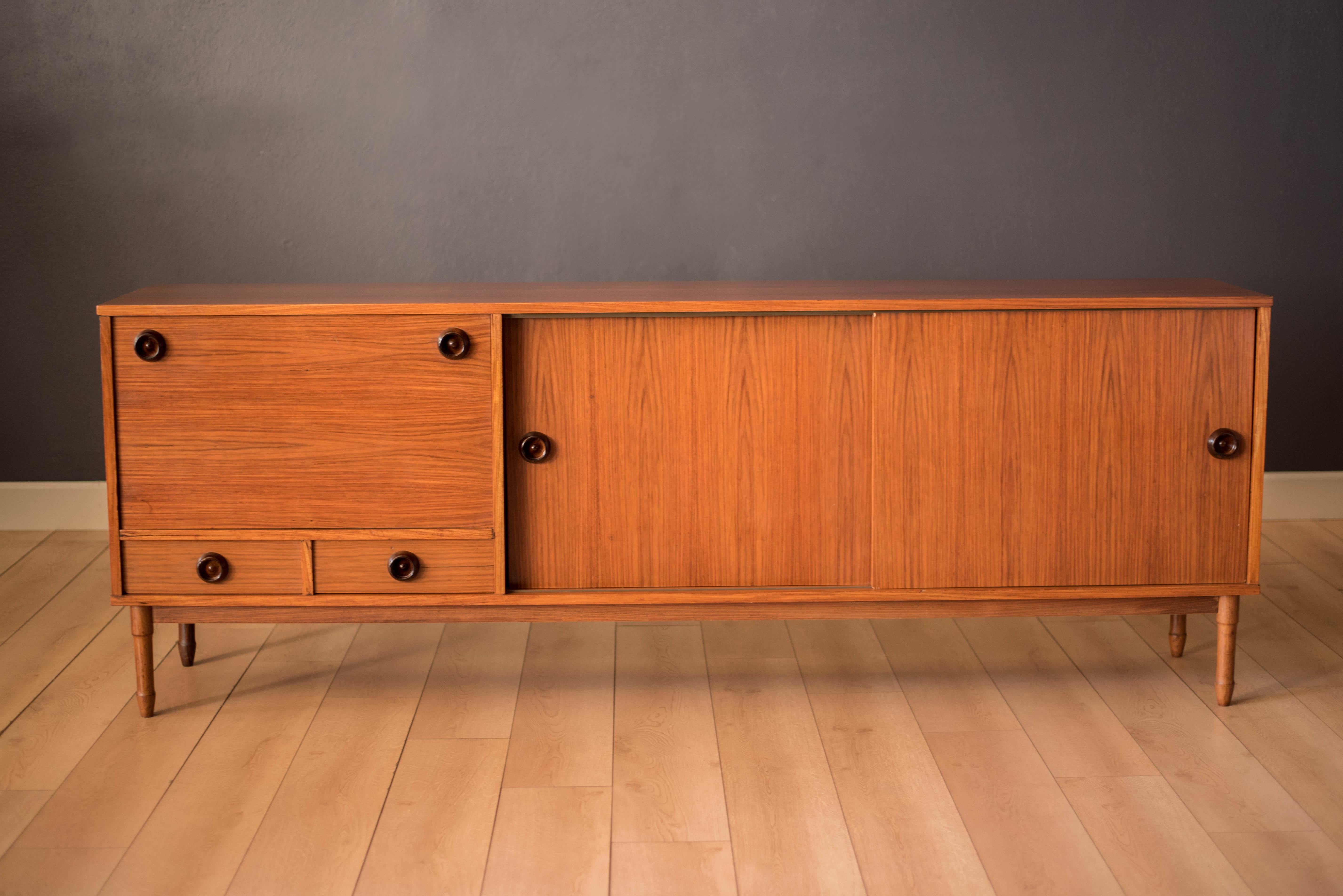 Vintage sideboard buffet in rosewood, circa 1970s. This piece offers plenty of storage including two drawers and open cabinet space with adjustable shelving. Features an additional drop front dry bar perfect for displaying bottles and glassware.