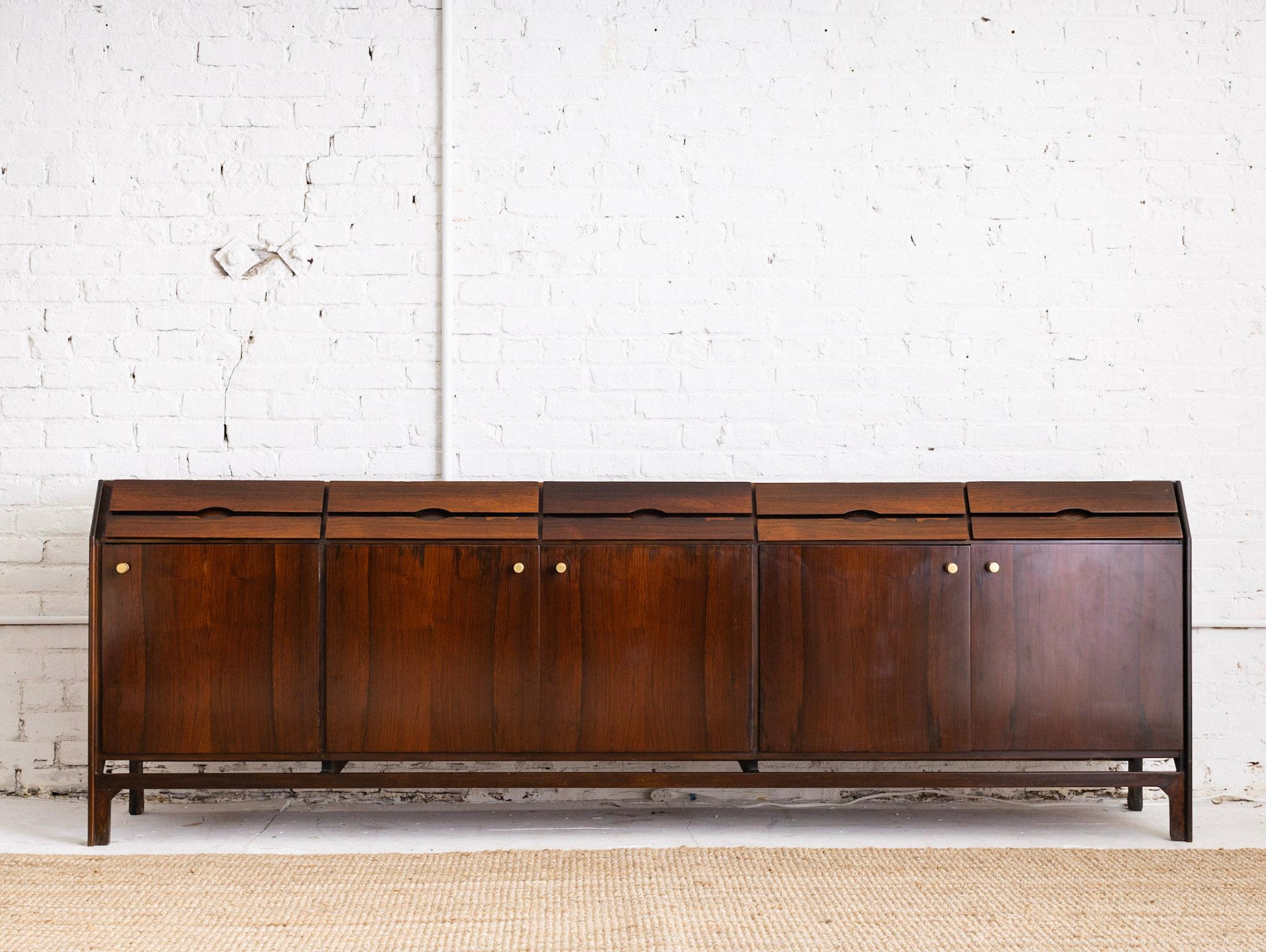 Mid Century Italian rosewood credenza. Five upper drawers and three lower cabinets with shelves. Rich rosewood grain throughout. Inner cabinets feature rosewood finish. Patinaed brass cabinet pulls. Sourced in Milan, Italy.