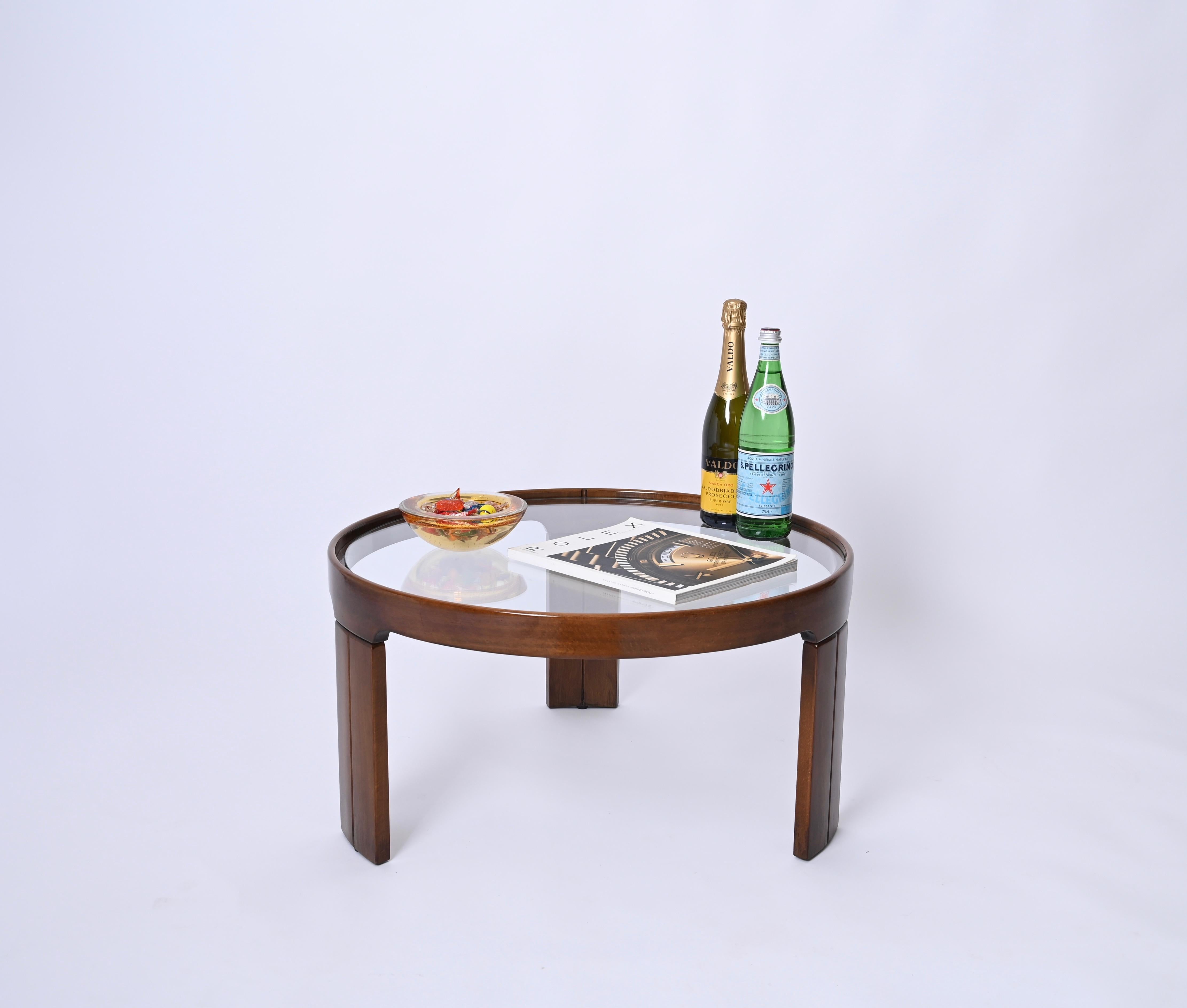 Gorgeous round tripod coffee table with crystal glass top. This stunning piece was produced by Molteni in Italy in the 1960s.  

Fully made in walnut, this side table features and incredibly elegant design, with three sturdy legs supporting a round