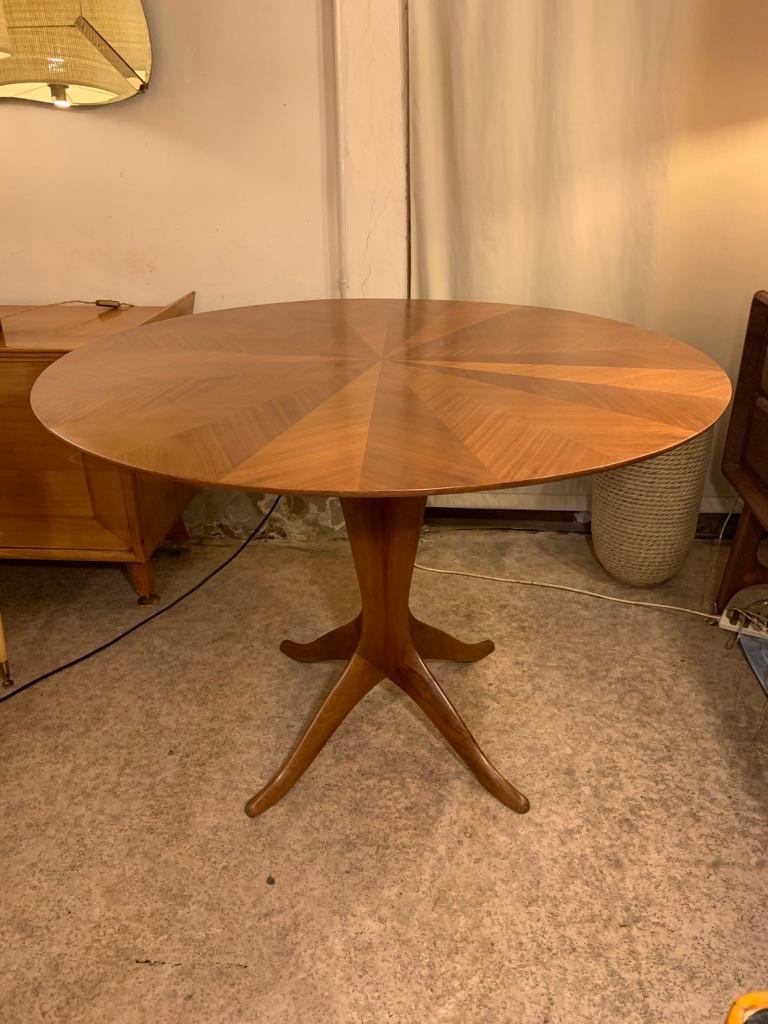 Italian round dining or center table from the 1950s, four-lobed base with four legs in solid walnut and a beautiful top with walnut arranged in a radial pattern. Interesting size makes it usable both for eating and as a table to be placed in the