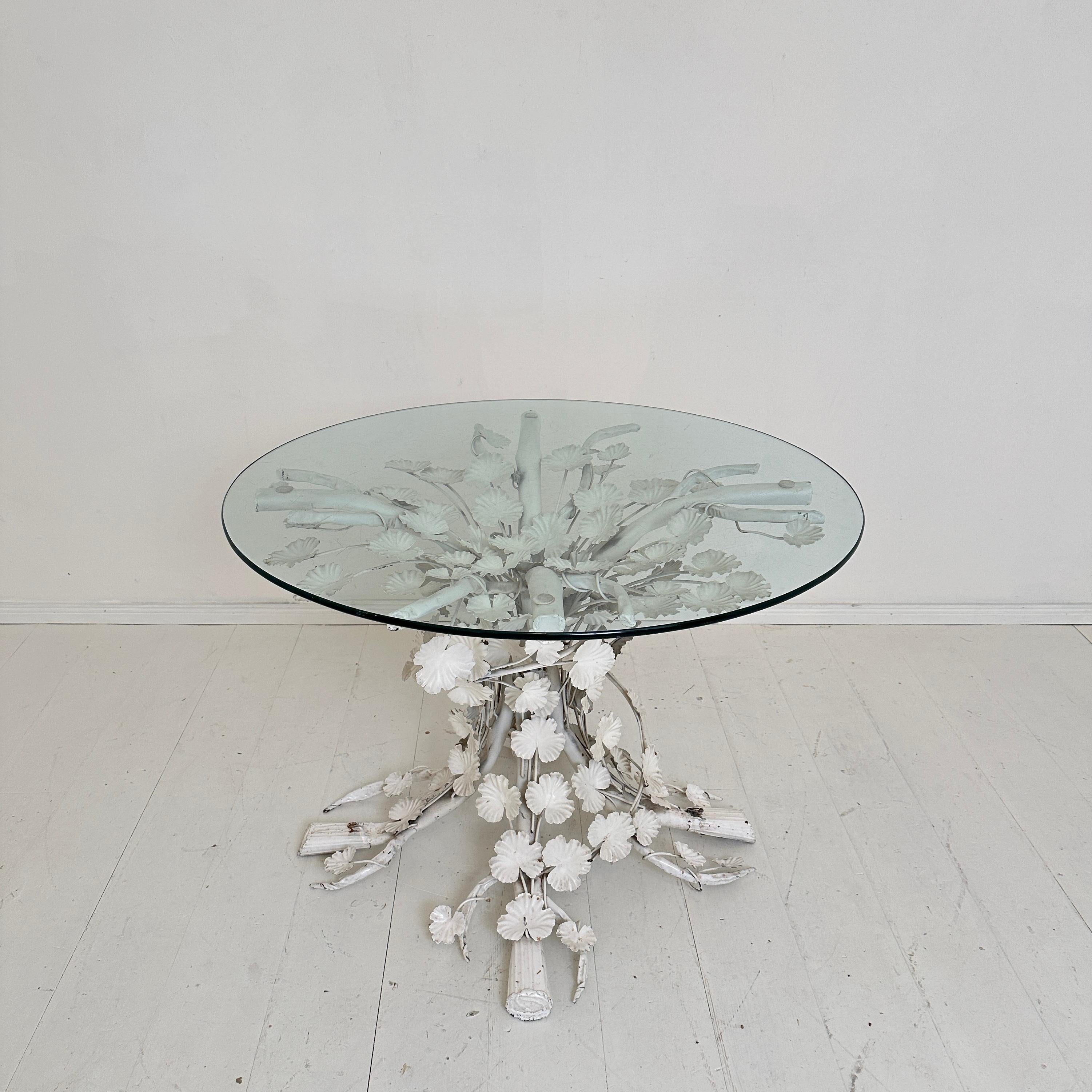 This Mid-Century Italian round dining table, crafted in the 1970s, is a stunning example of modernist elegance with a touch of playful design. The table features a striking white metal base intricately fashioned into a floral-inspired pattern,