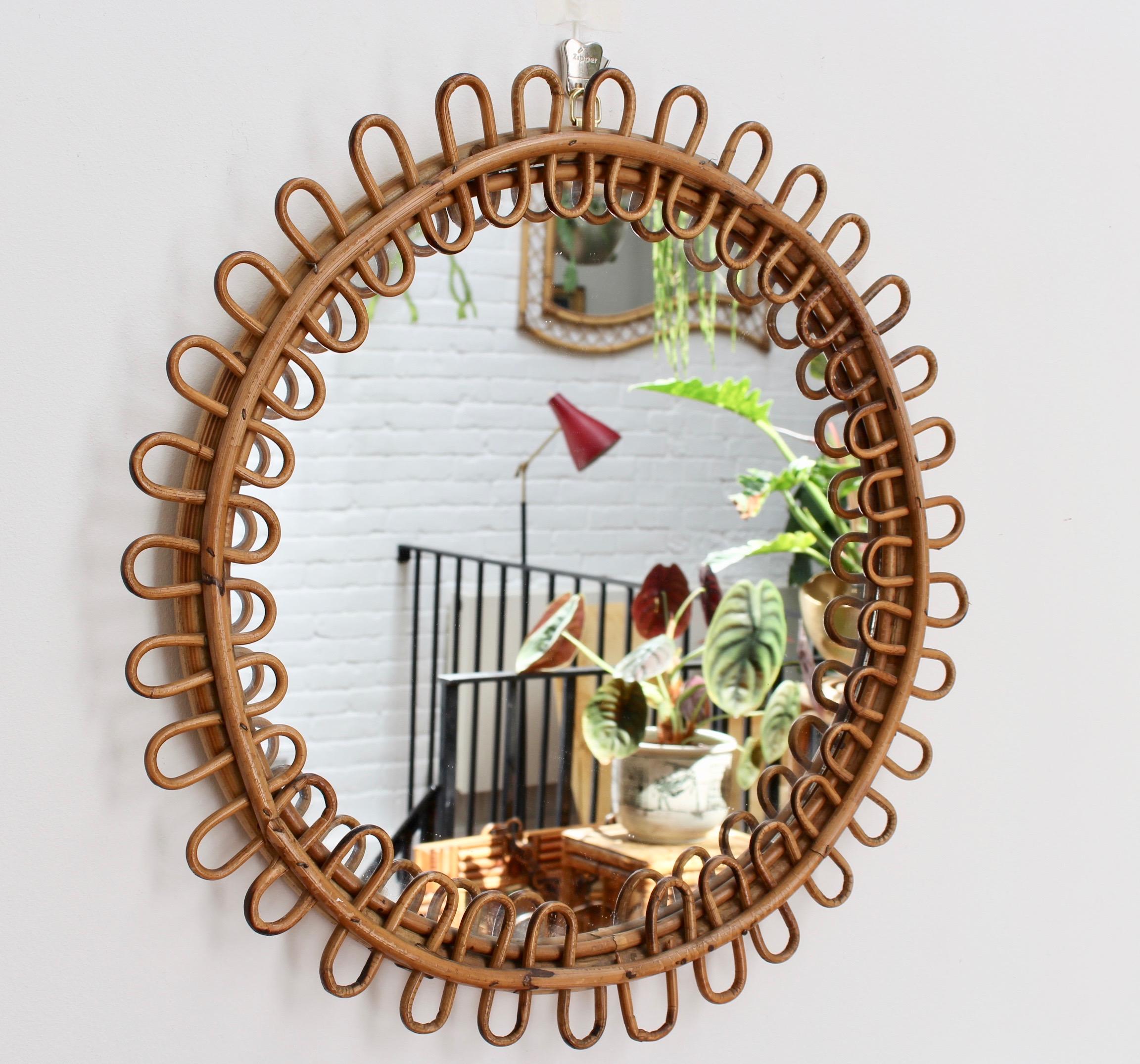 Midcentury Italian round rattan mirror (circa 1960s). Chic and stylish circular sunburst mirror with cane frame and undulating rattan border. Let the sunshine in to your home and your life. In fair vintage condition commensurate with age and usage.