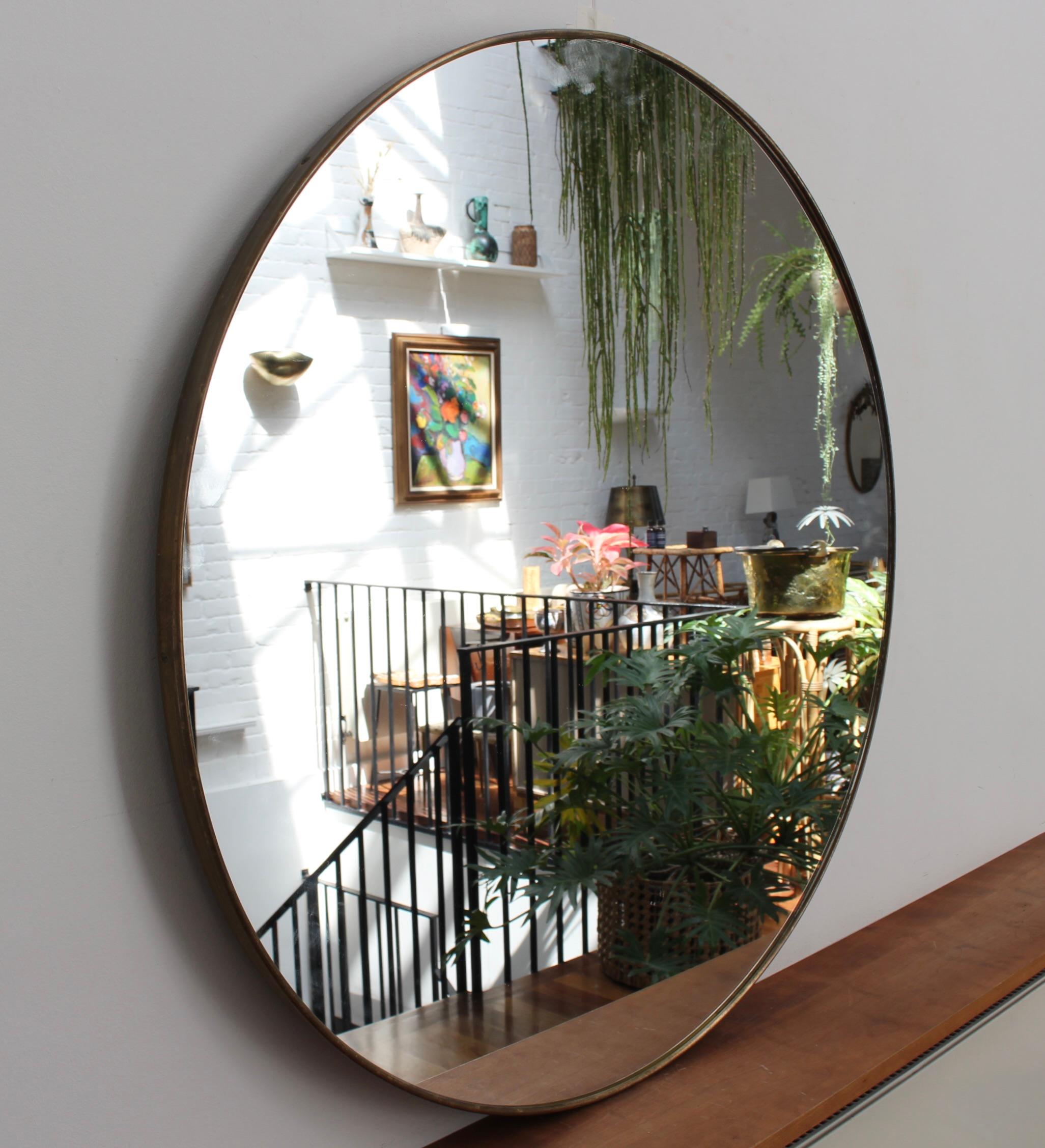 Mid-century Italian wall mirror with brass frame (circa 1960s). The mirror is a perfectly shaped circle in a Modern style. It is in good overall condition. A beautiful, aged patina develops on the brass frame. A sturdy backing provides structural