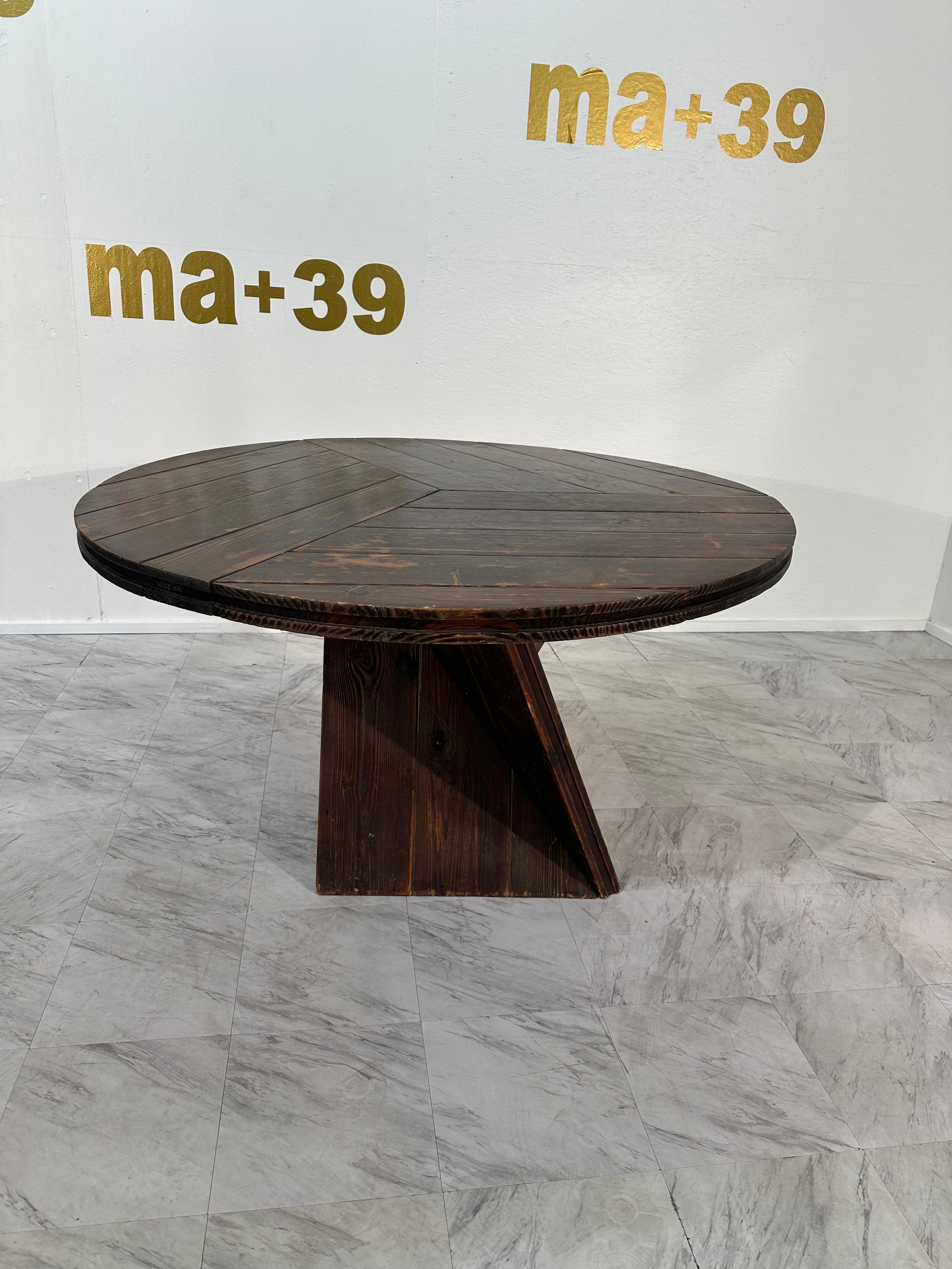 This stunning Italian round dining table from the 1960s showcases timeless craftsmanship and rustic elegance. Made entirely from rich, dark wood, this table features a unique geometric pedestal base, adding a bold statement to any dining space. Its