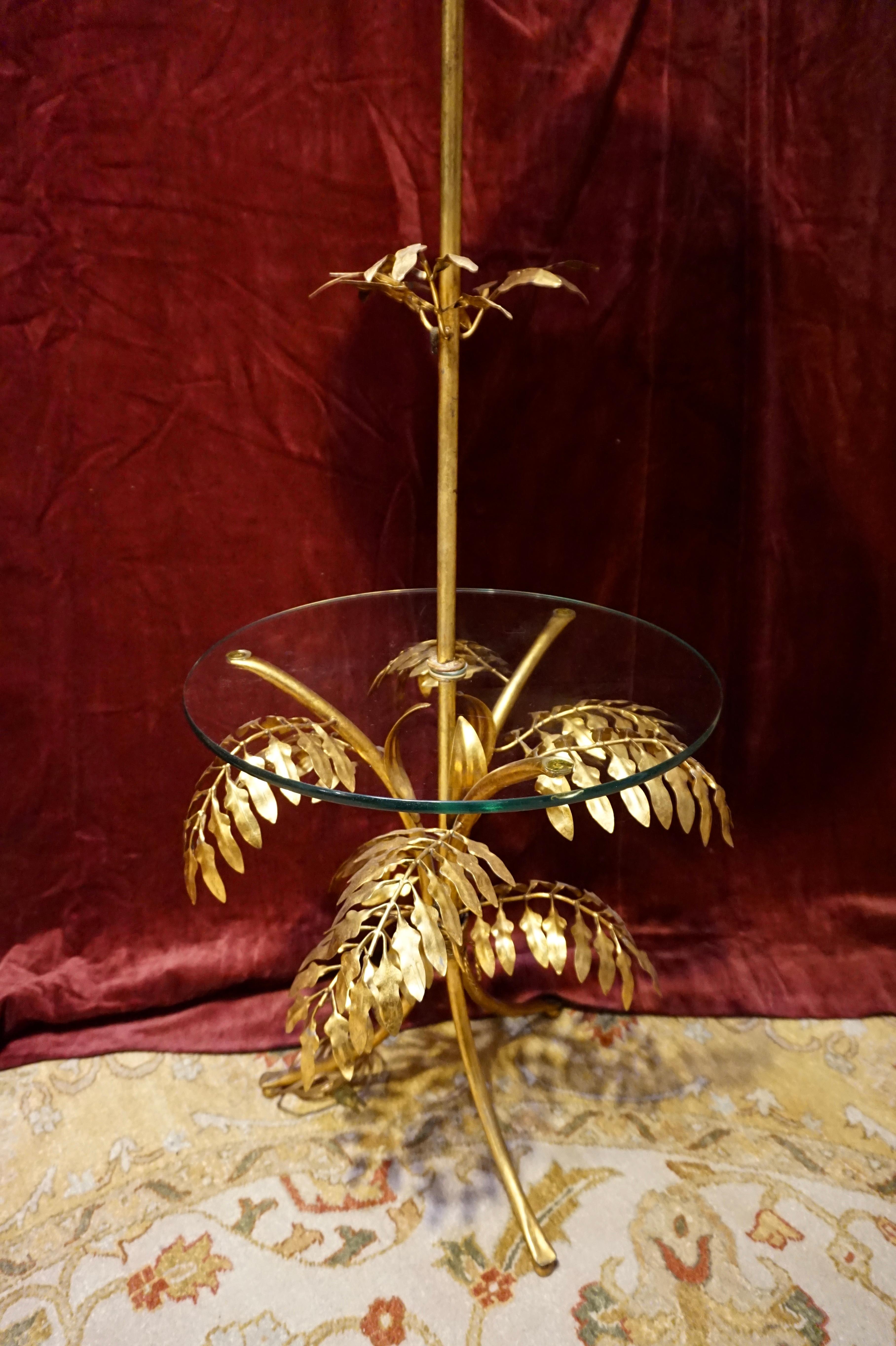 Rare Mid Century Italian gold leaf floor lamp. Beautifully hand constructed from metal with central glass that serves as a side table. Lovely decorative cascading leaf pattern is featured in this artistic and conversational lamp. Several tags that