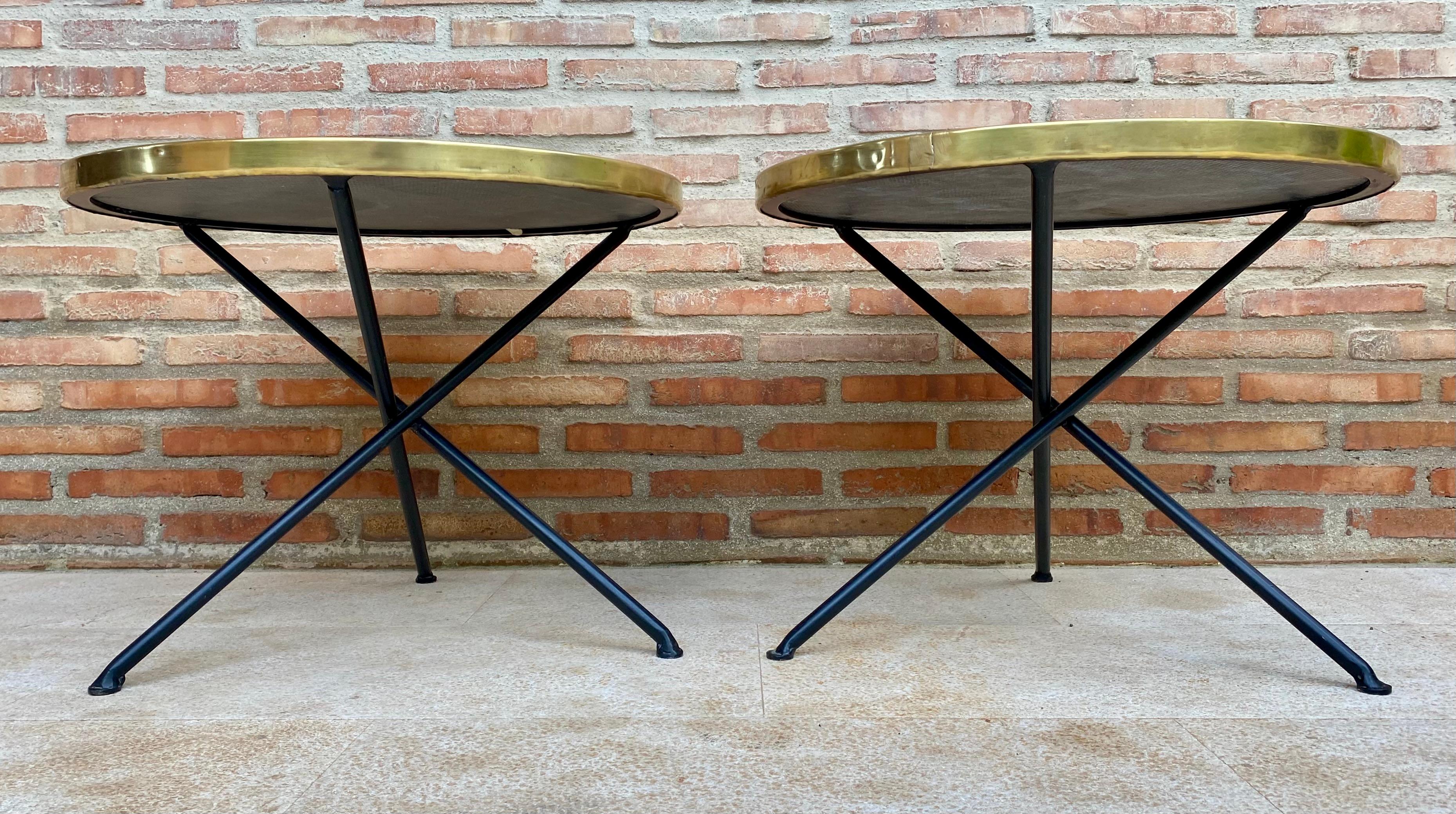 Beautiful pair of vintage side tables, Italian style, with a round base in black and white marble and a brass edge that rests on crossed iron legs. 
These side tables look good both in a dining room and in a bedside table room. 
These are a