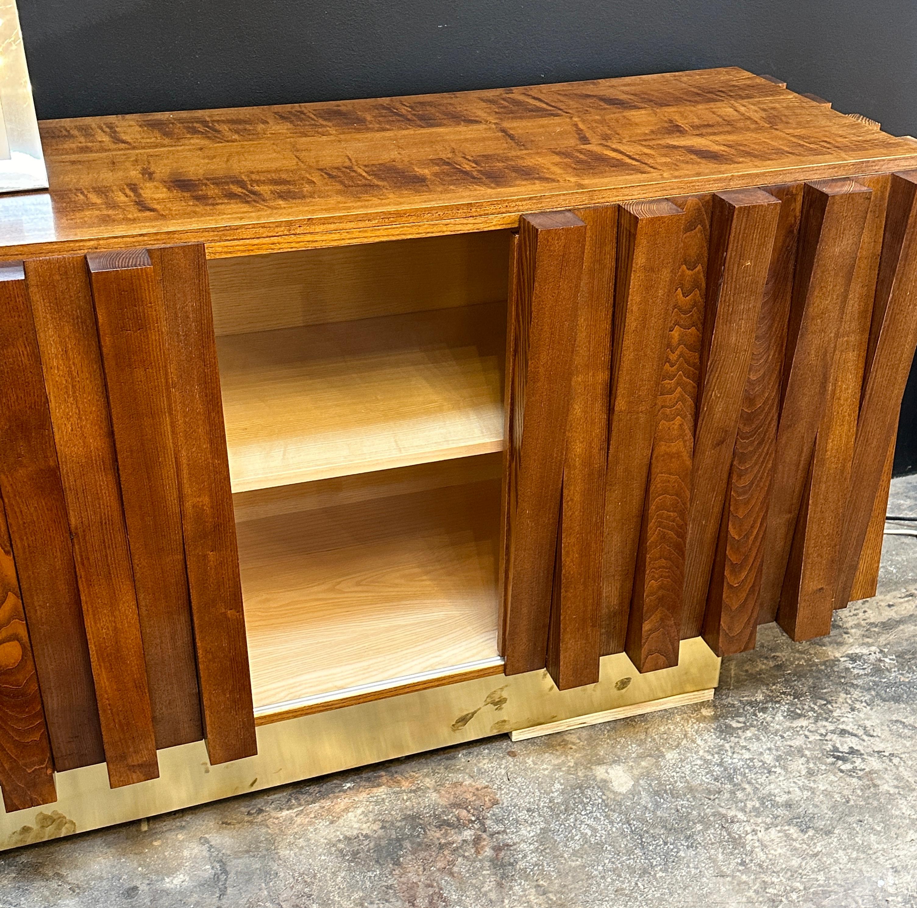 This mid-century wooden sideboard features a unique vertical slat design on the front. The rich wood tones give it a warm and inviting look, while the natural grain adds texture and depth. The cabinet doors slide to reveal spacious shelves, making