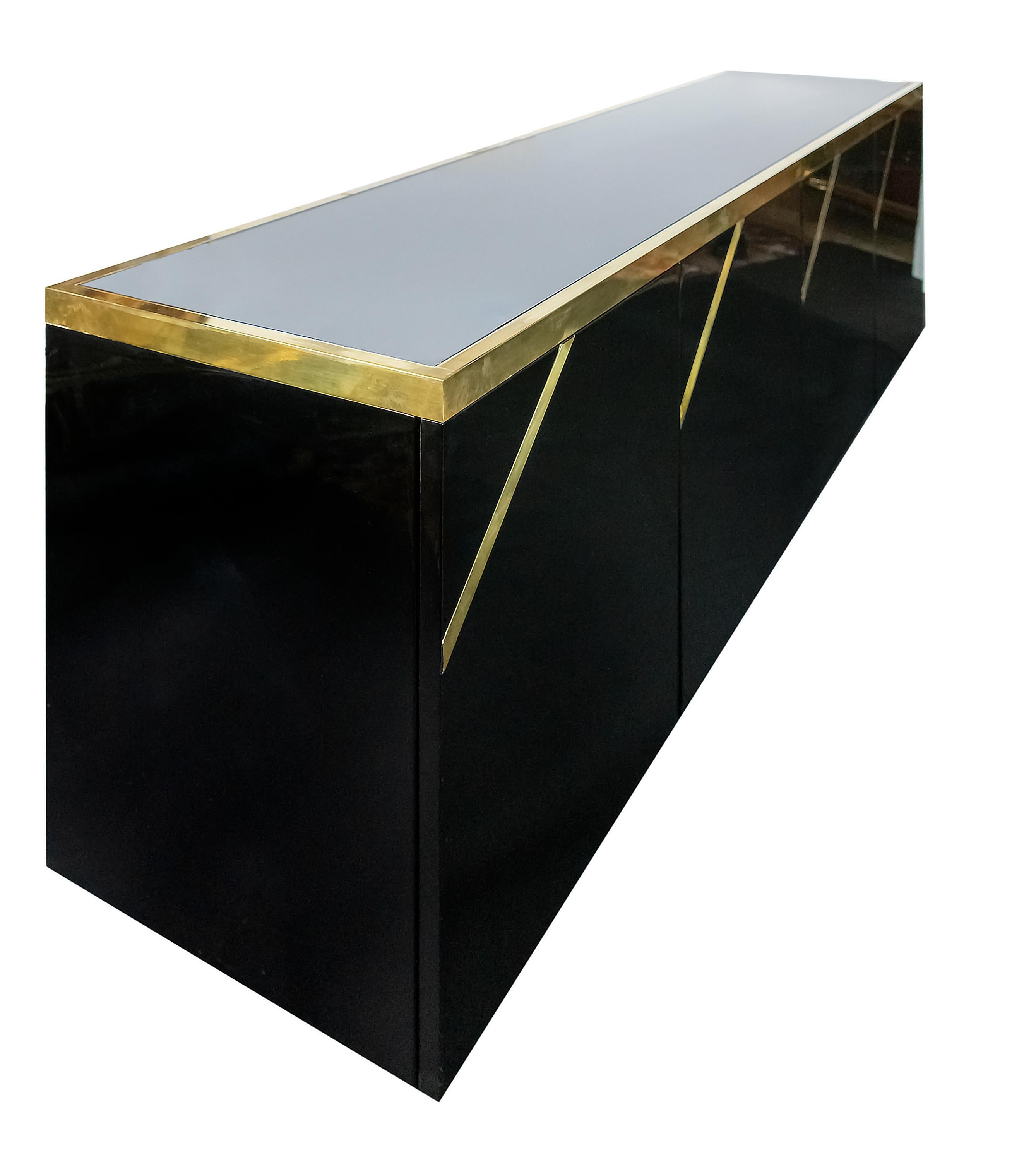 Italian vintage black color polished surface sideboard / commode from 1970s in the style of Willy Rizzo / Maison Jansen.
Doors are decorated with inlaid brass stripes details. Opens by pressure.
The top is decorated with thick and massive solid