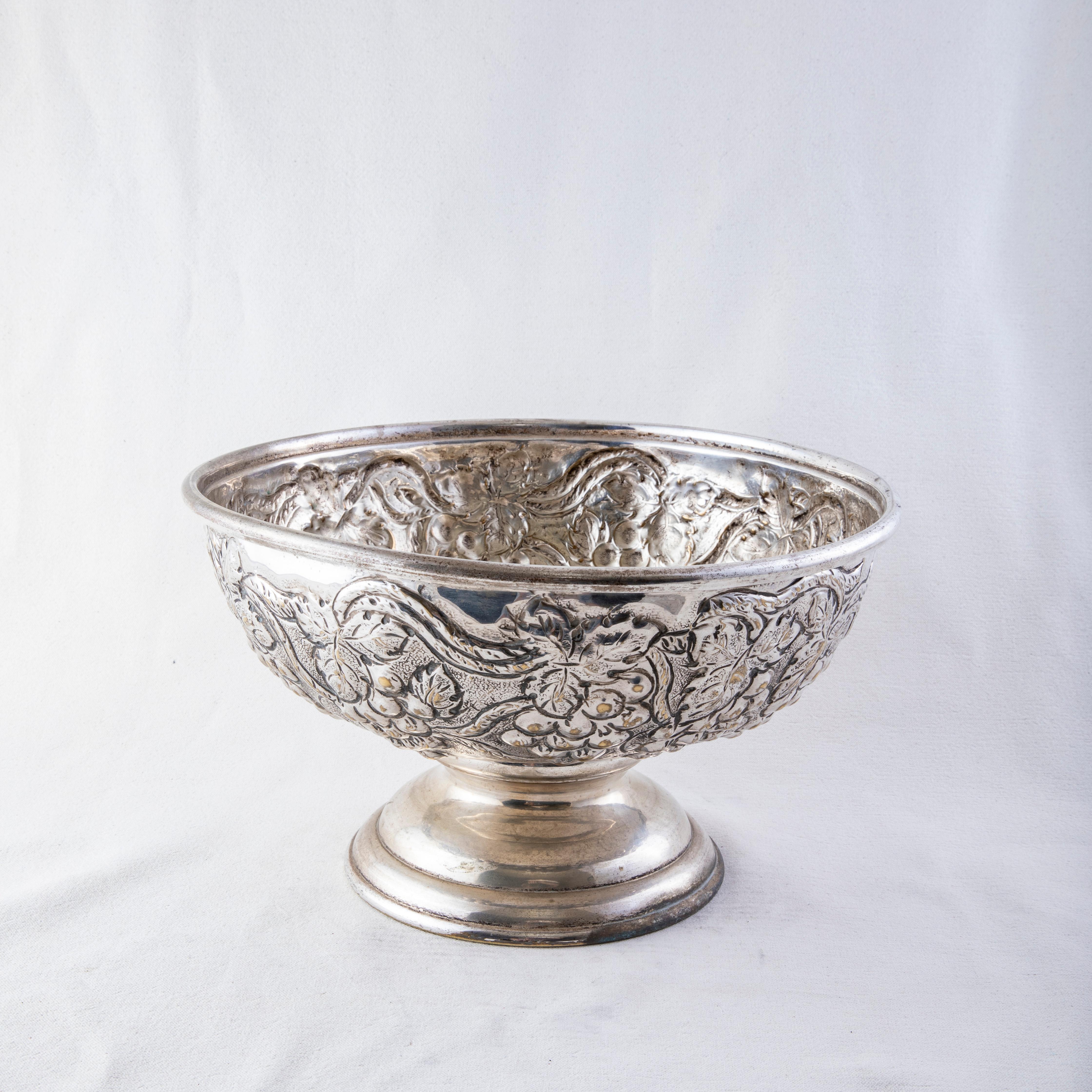 This large mid-twentieth century Italian hotel champagne bucket features a hand hammered repousse grapes and grape leaf motif. The bucket rests on a footed base and can accommodate up to three bottles. A quintessential bar piece, this large