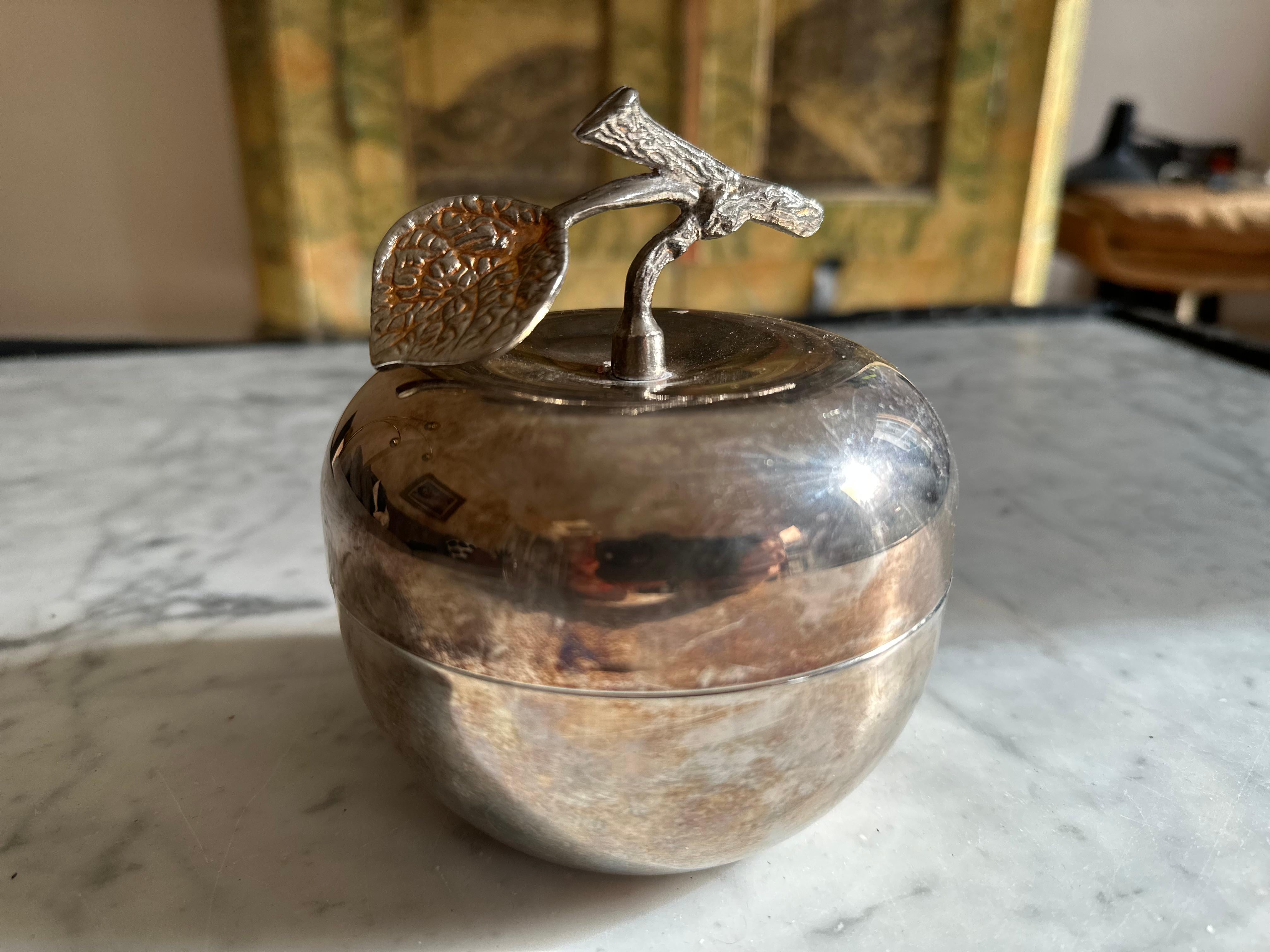 Transport yourself back to the stylish era of the 1970s with this charming vintage Italian apple-shaped lidded box. Crafted with meticulous attention to detail, this silver-plated masterpiece boasts a small branch as its distinctive handle, adorned