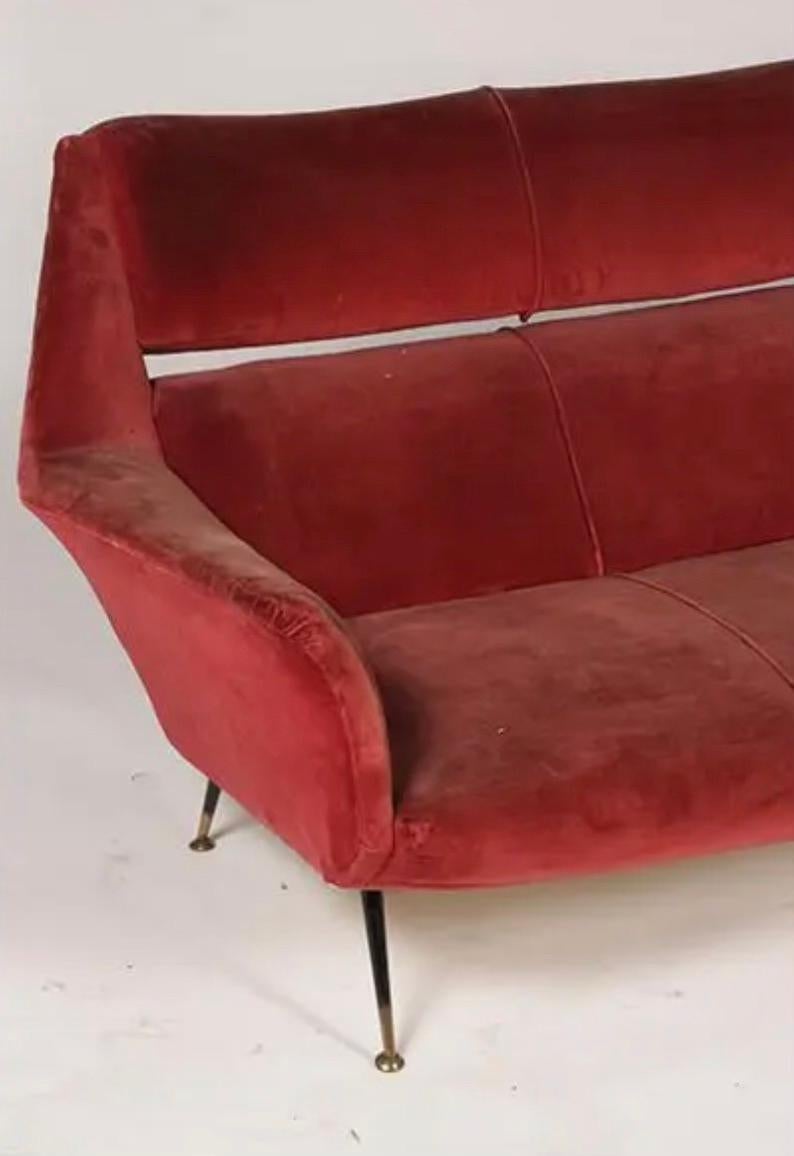 An Italian mid-century modern sofa has flared arms and resting on bronze tipped iron legs circa 1960