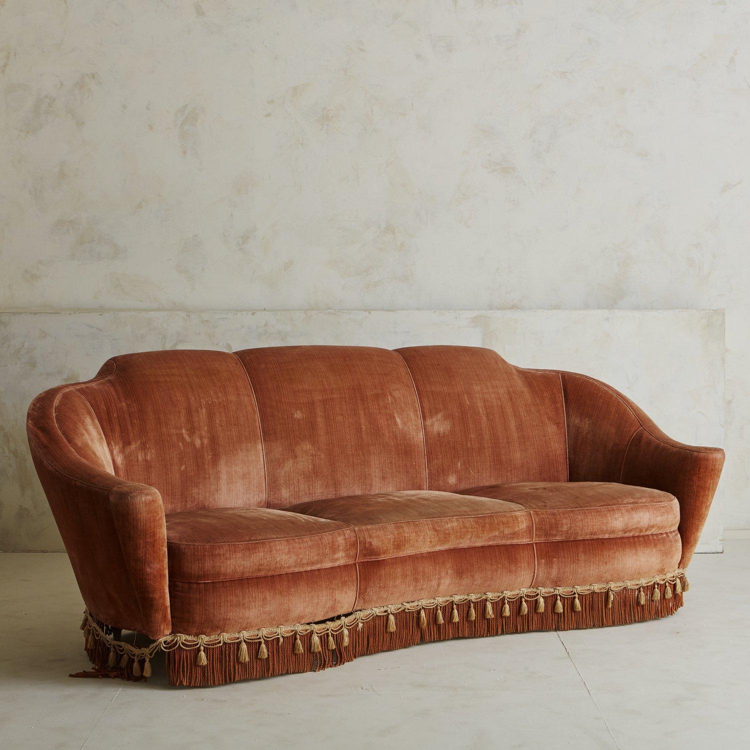 A mid-century sofa in original pink velvet upholstery. This sofa has an elegant frame with curved arms and fringe details (can be removed during reupholstery). Sourced in Italy, 20th century.
