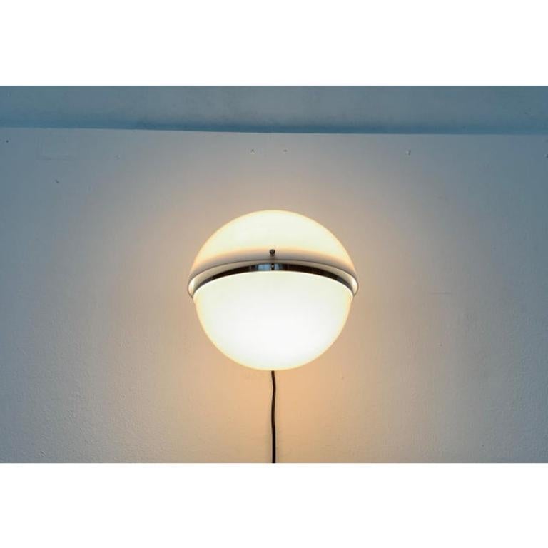 Applique sphérique de Guzzini d'après un design de Luigi Bandini Buti pour Kartell.

Les deux moitiés du diffuseur en plastique sont finies en blanc translucide. Le support est un anneau métallique qui sépare les deux hémisphères. Le diamètre de la