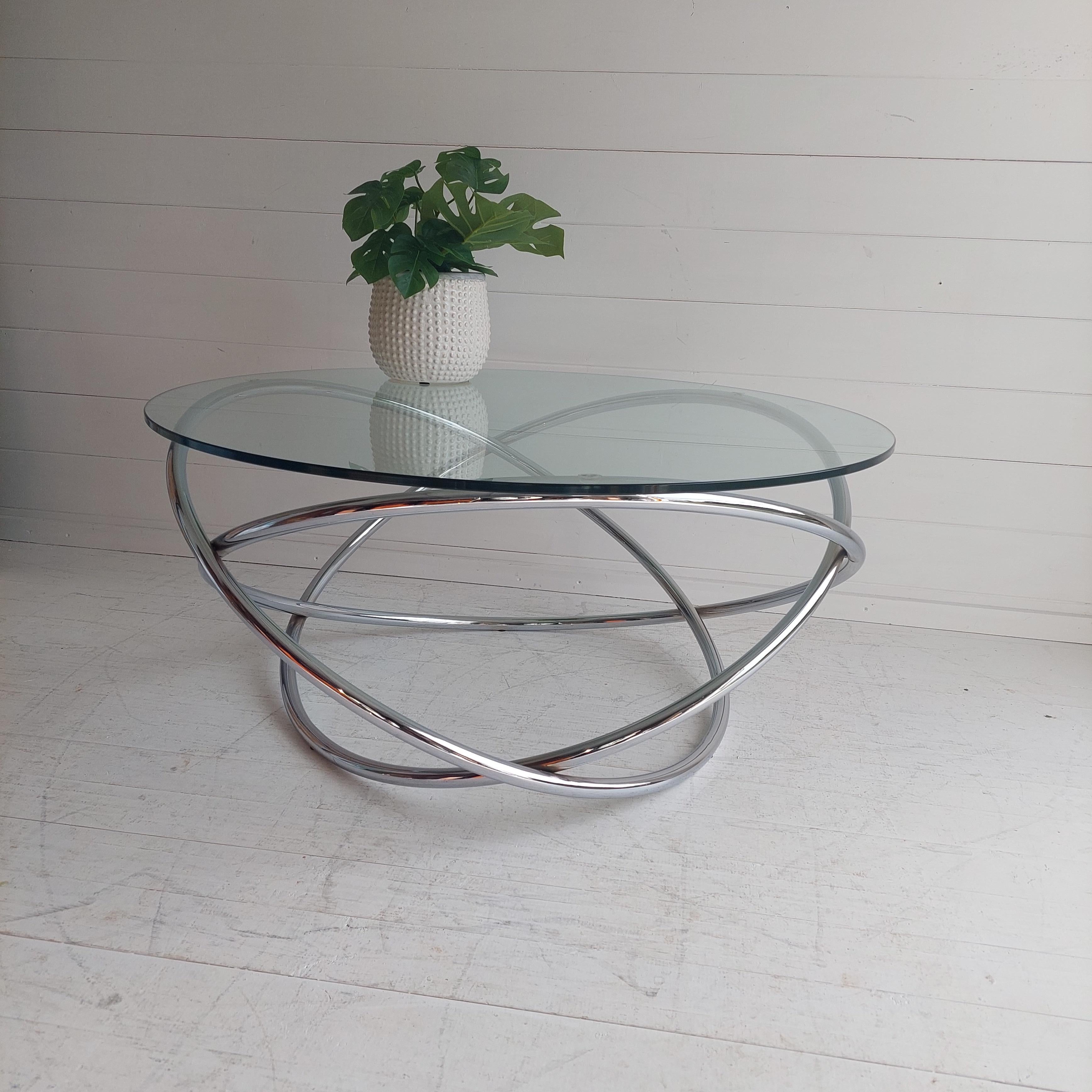 A Stunning round glass and tubular metal coffee table with a spiral pedestal base in a space age style.
Mid century italian minimalist swirl coffee table. 
Great top glass and chrome base minimalist swirl coffee table probably made by Miniforms,