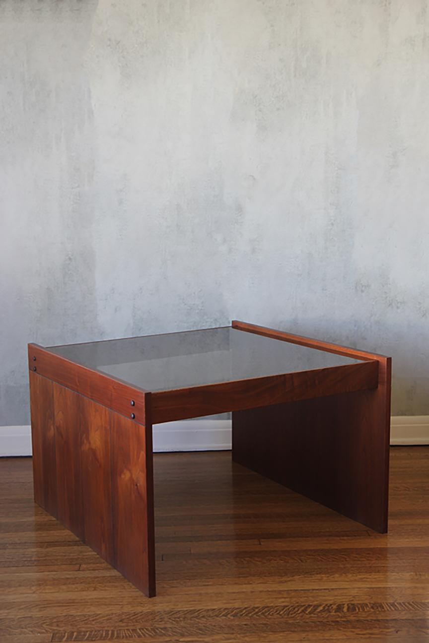 Magnifique table basse en palissandre massif avec plateau en verre fumé gris. Fabriqué dans le style de Kazuhide Takahama, en Italie, dans les années 1960. Le cadre de la table en bois à la forme brutaliste est solide et de très bonne facture. Le