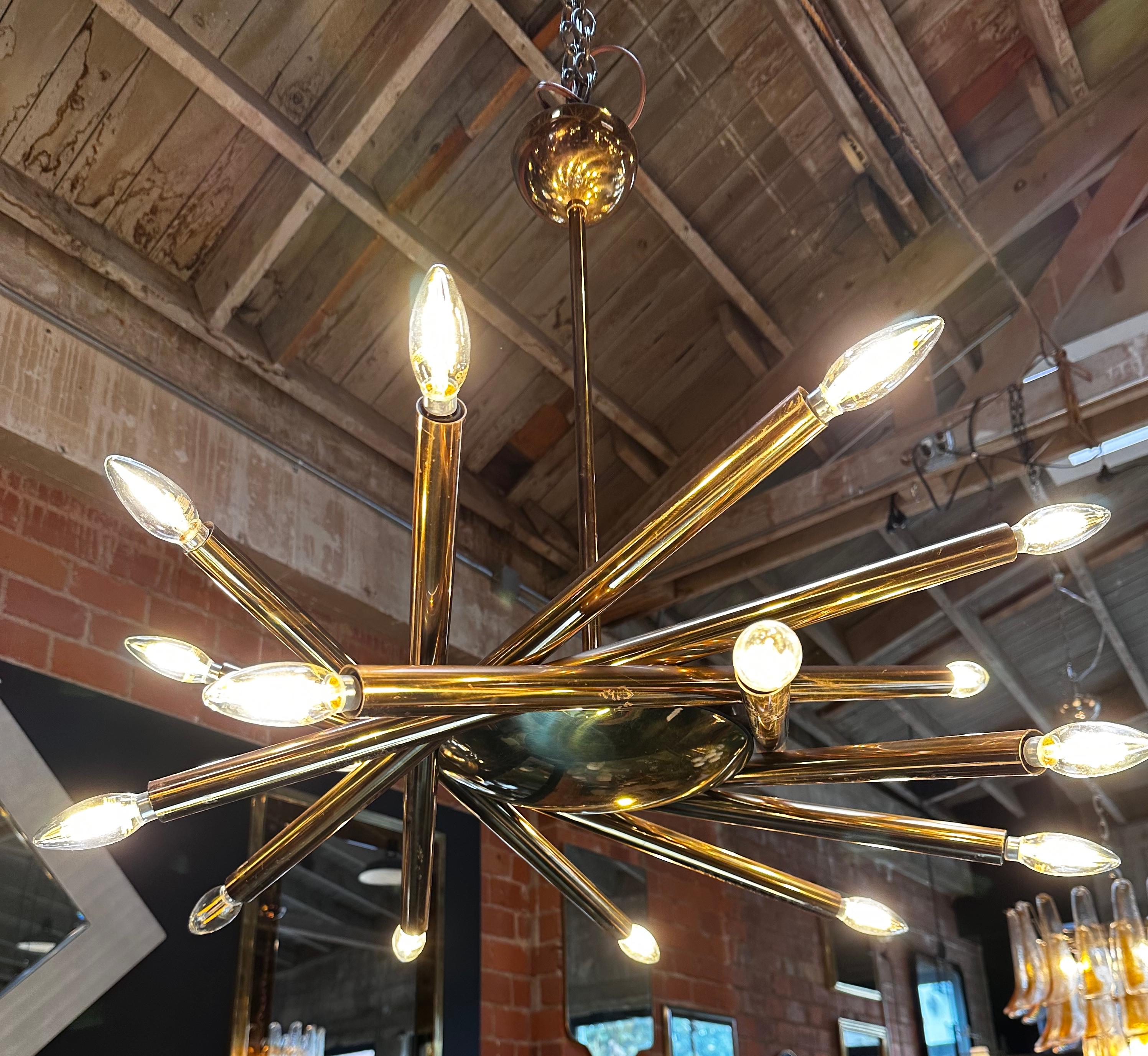 The Mid Century Italian Stilnovo Orbit Chandelier, crafted in brass and originating from Italy in 1955, is a stunning example of mid-century modern design. This remarkable chandelier is an embodiment of elegance and sophistication, featuring a host