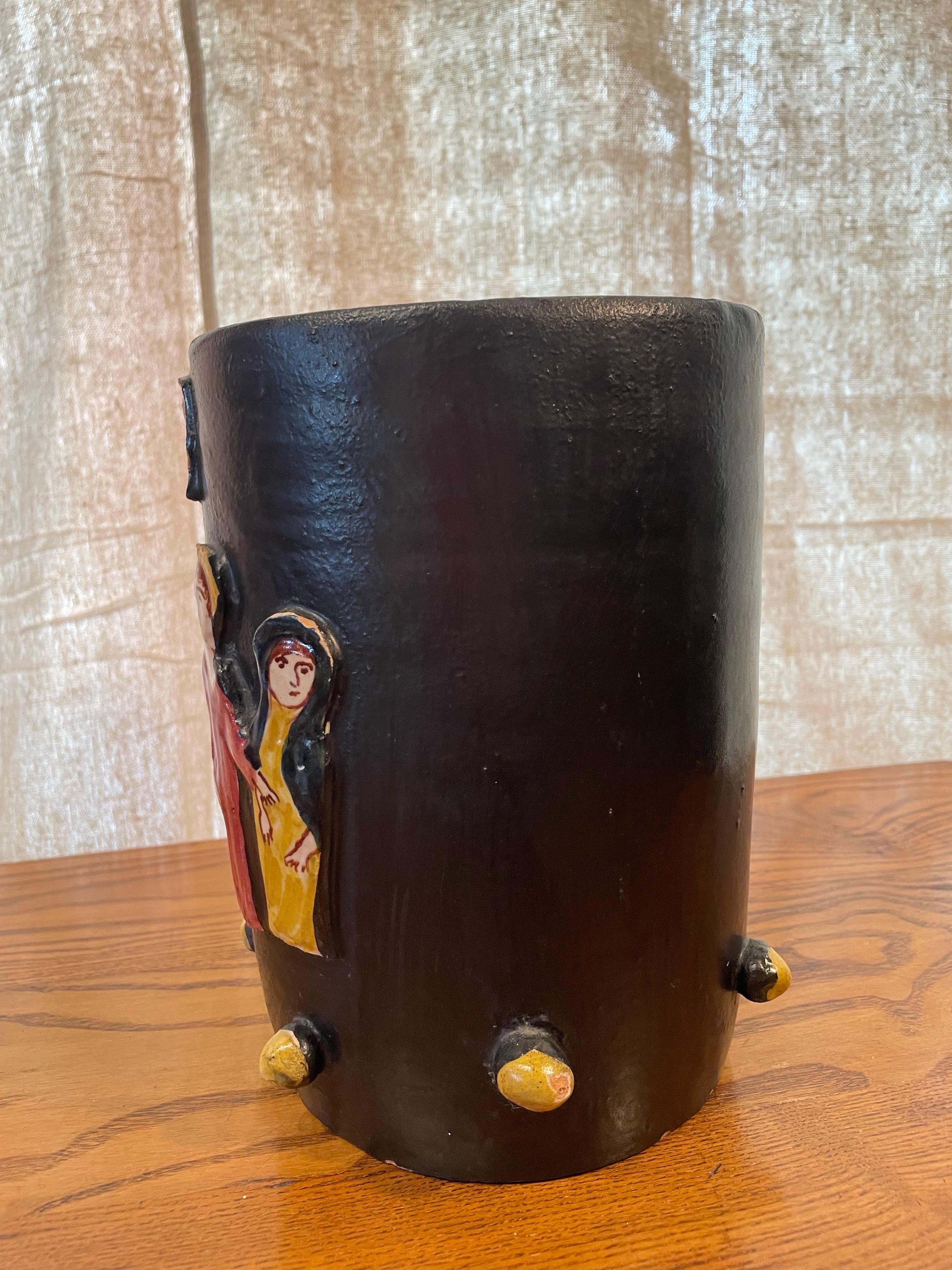 Un sorprendente vaso in ceramica da studio italiano della metà del secolo scorso, con figure applicate in rilievo e caratteristici accenti arrotondati. Questo vaso cilindrico è smaltato in un ricco nero che crea un contrasto drammatico con quattro