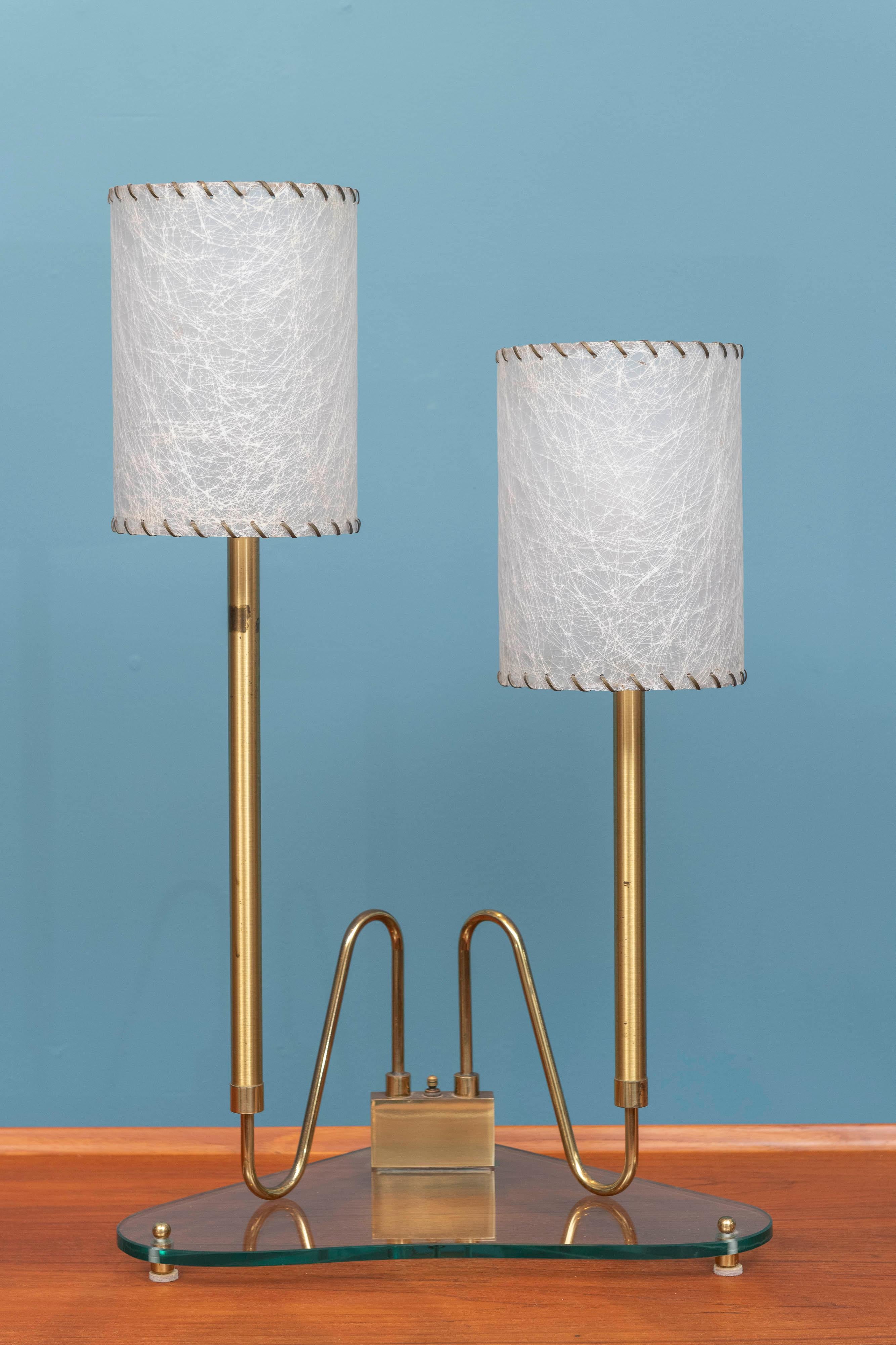 Mid-Century Italian table lamp. High quality construction and attention to detail comprising a cut glass triangular base on brass feet with stylized arms and vintage looking shades. Both sockets wired for US standard bulbs with a central switch