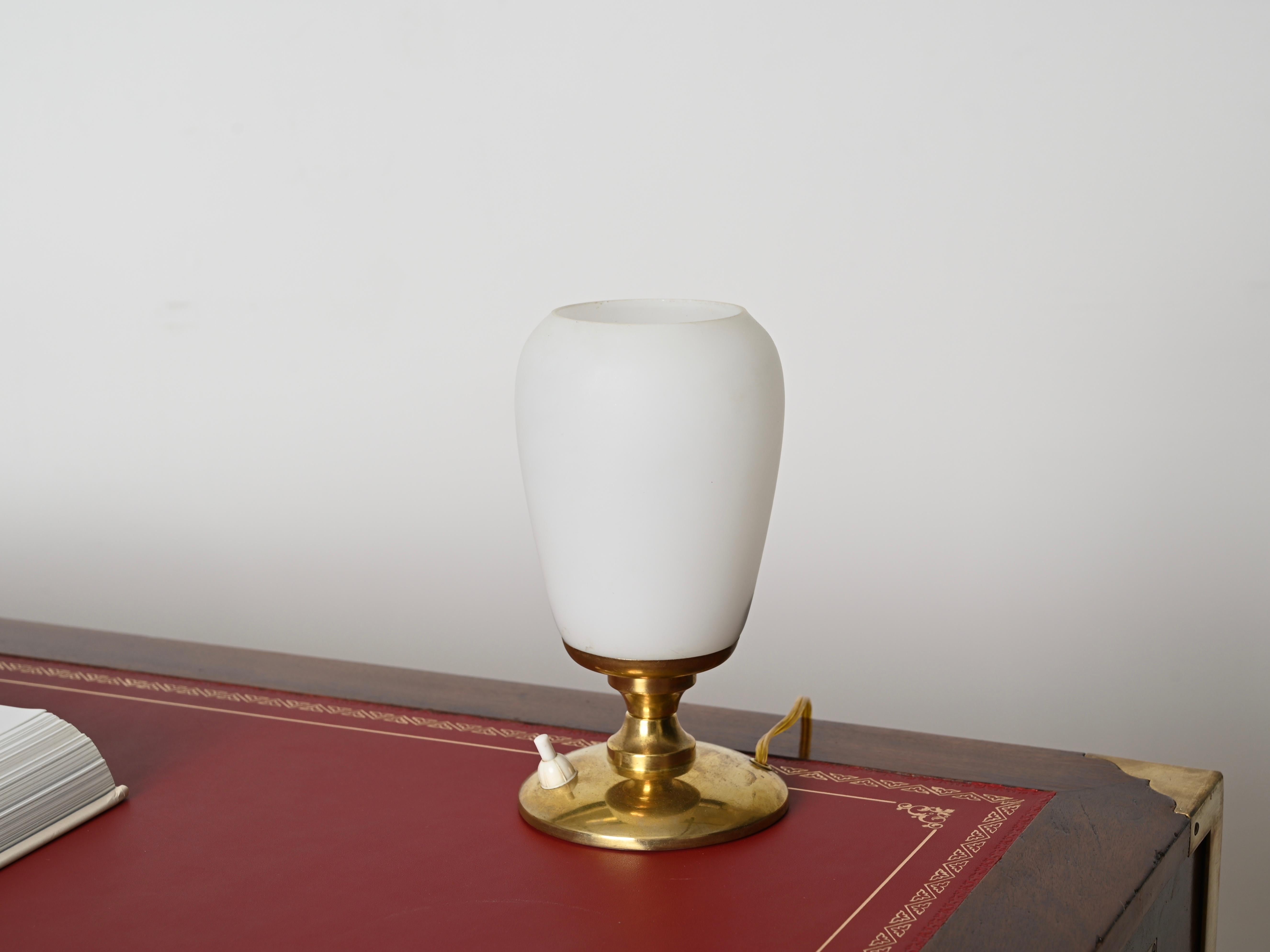 Delightful Italian table lamp in brass and opaline glass. This lovely lamp was designed in Italy during the 1950s.

In amazing conditions and with no chips, the brass on the lamp has a beautiful gold patina which has not been polished to preserve