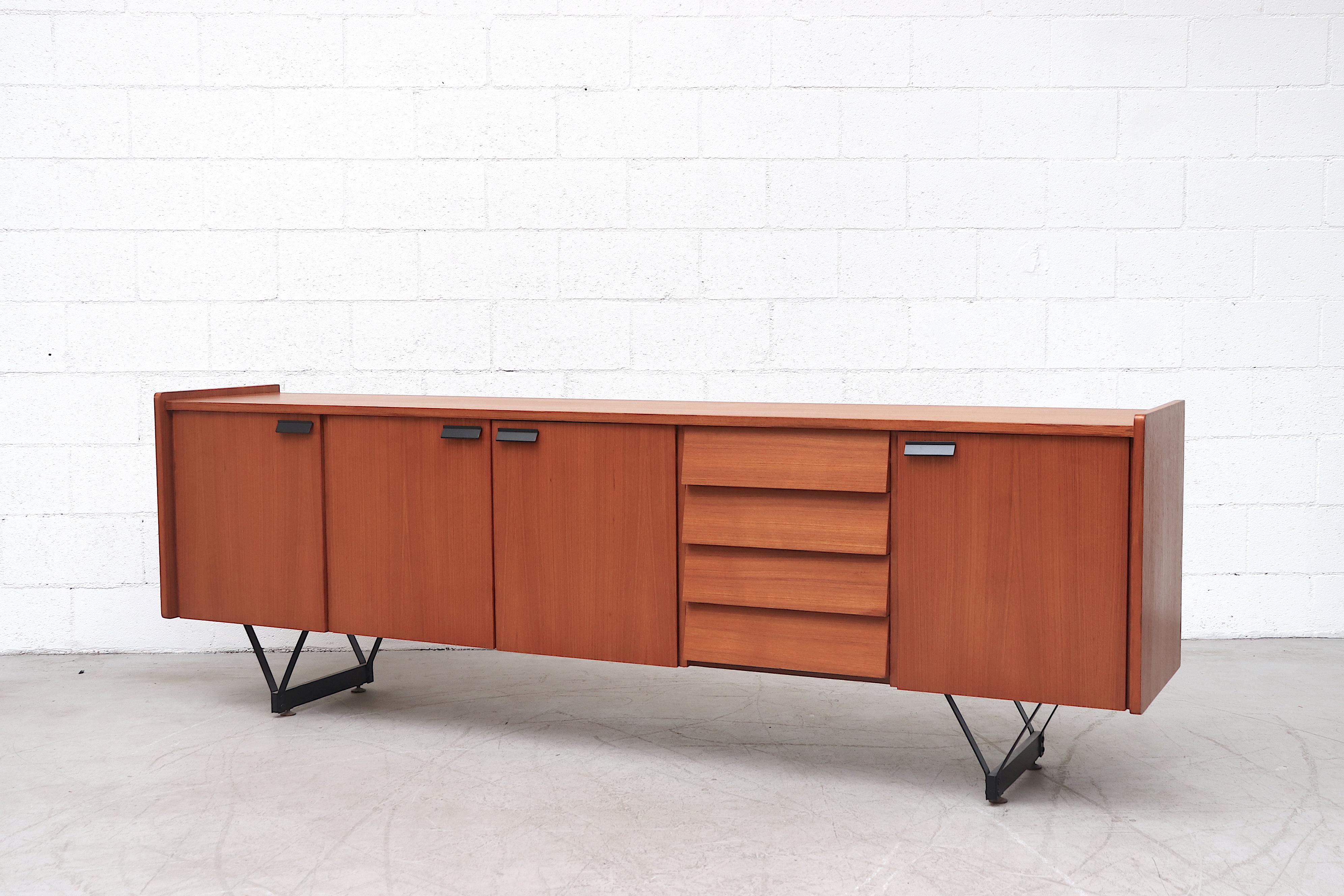 Beautiful Mid-Century Italian teak credenza with black enameled architectural legs with cantilevered drawers and large storage cabinets. Handsome black enameled metal handles. Lightly refinished. In good condition with some wear consistent with use