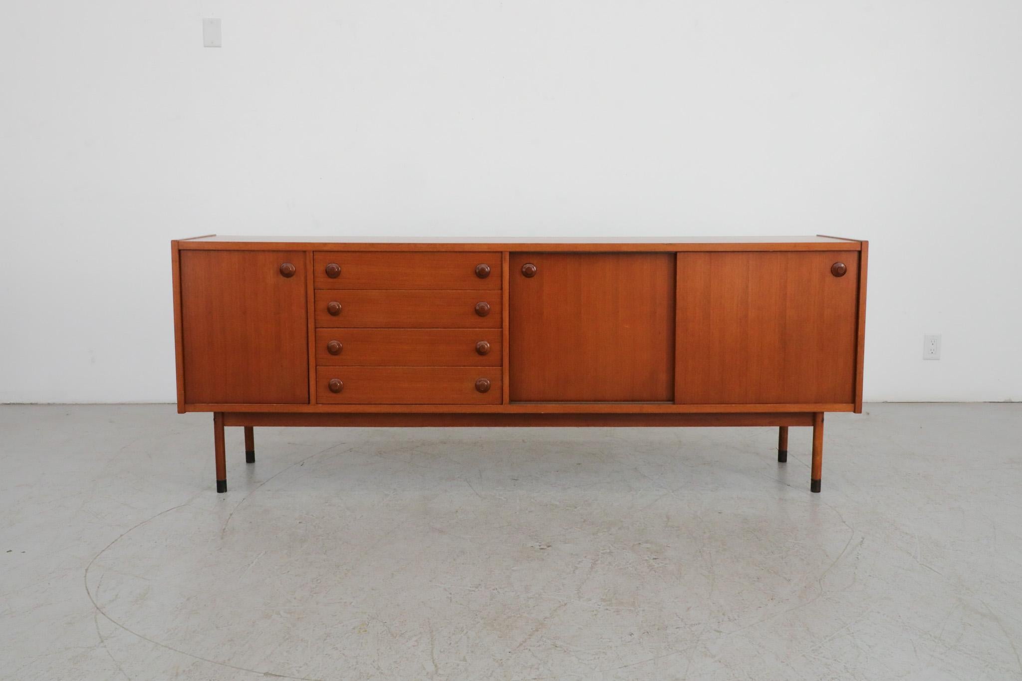 Stunning, Italian mid-century sideboard, circa 1960s. Crafted out of beautifully toned teak with four center drawers and two storage cabinets. The top drawer still contains the original silverware/utensil dividers and the credenza has a sliding door