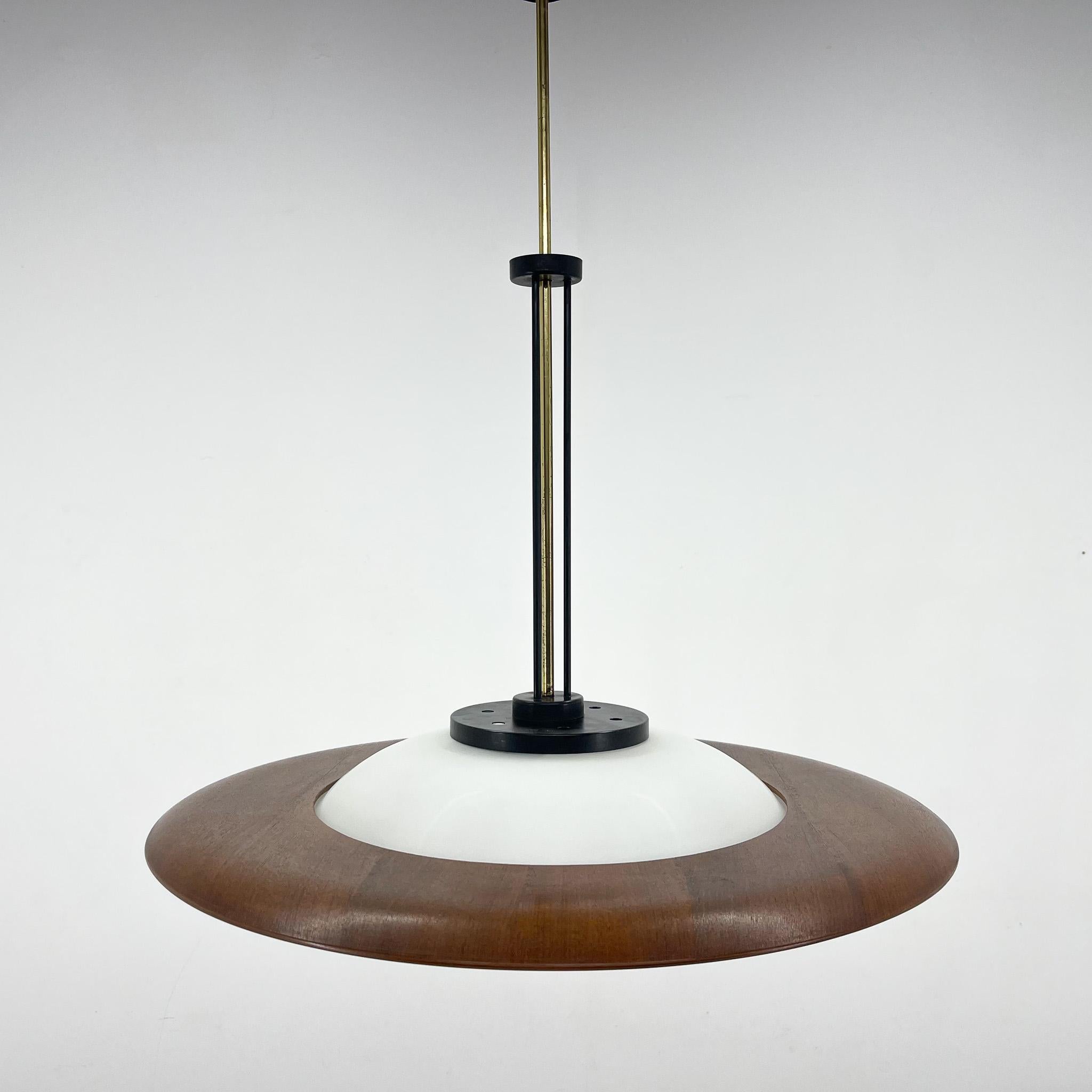 A beautiful pendant light straight from Italy, reminding of a UFO, made in the late 1960's. It is made of milk glass, teak wood, brass and metal. A beautiful timeless piece of lighting.