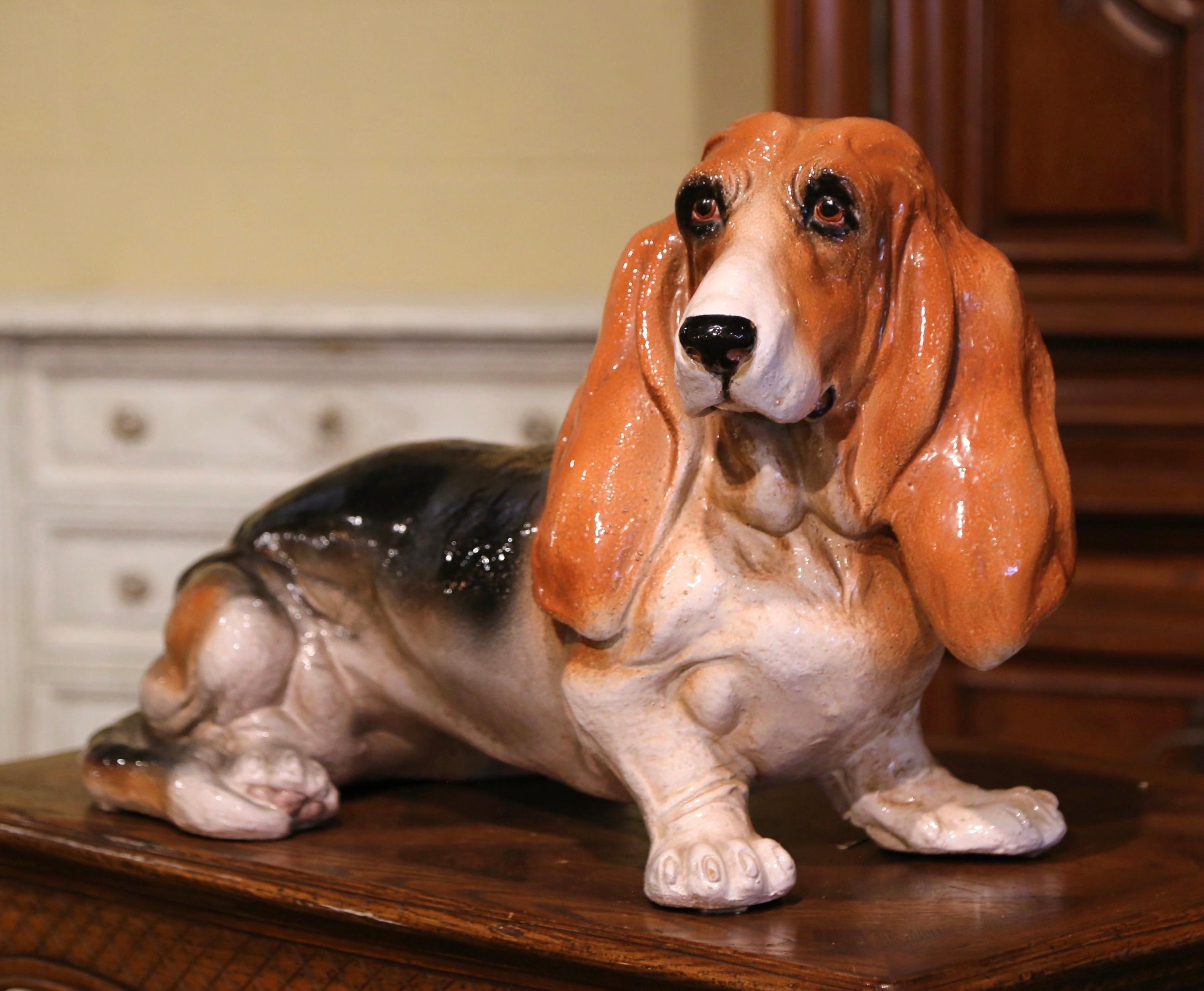 Dog lovers will appreciate this realistic vintage hound dog. Crafted in Italy, circa 1950, this charming terracotta statue is life-size, and depicts a sitting basset hound gazing forward. Boasting lovely russet, black and white colors that