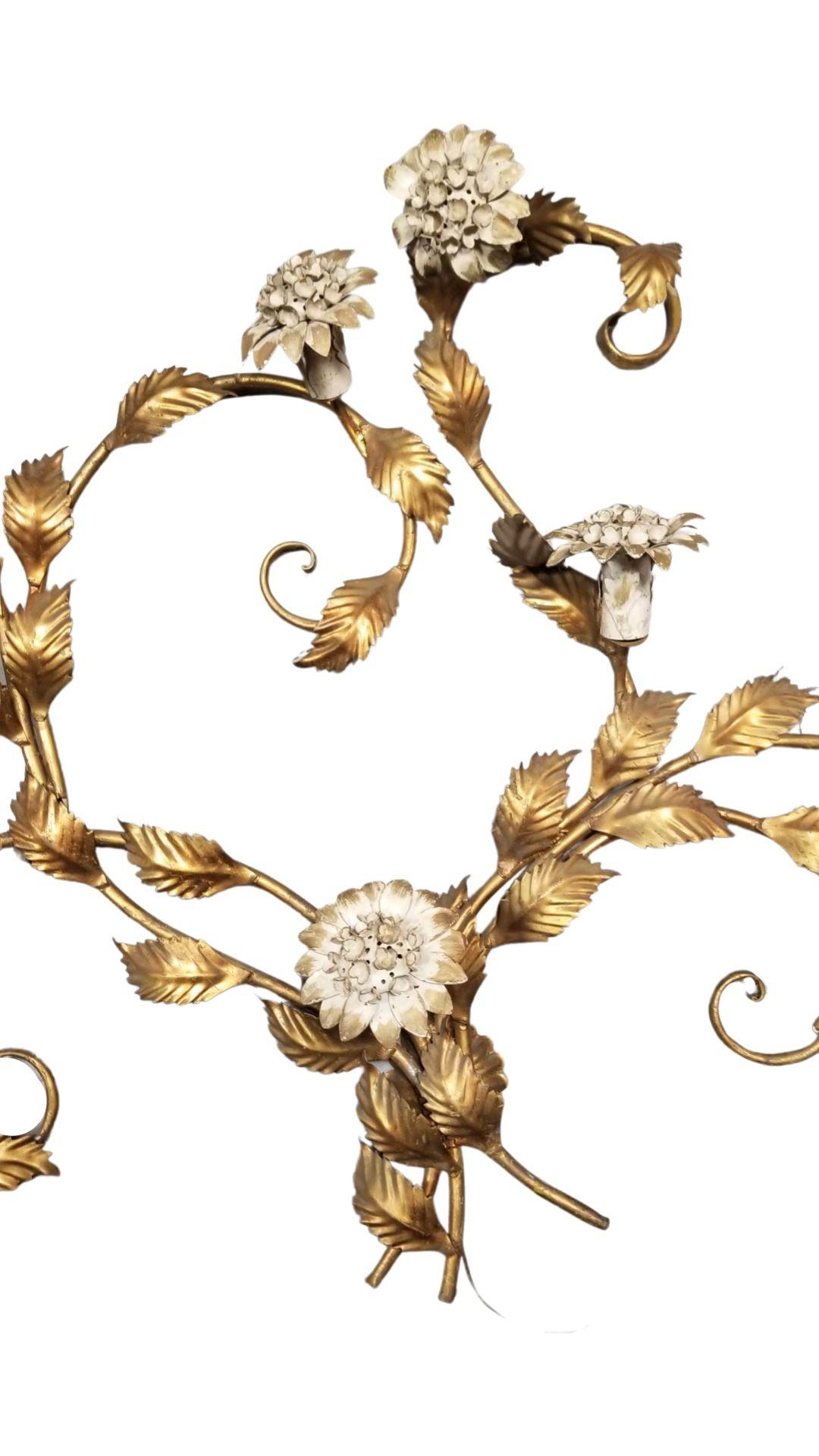 Mid-century era Tole wall sculpture light up wall sconce in the form of curling vines in brass enameled white illuminated flowers. Each flower is on a hinge for easy bulb replacement. Flowers lay forward when hung on a wall.

A stunning Italian