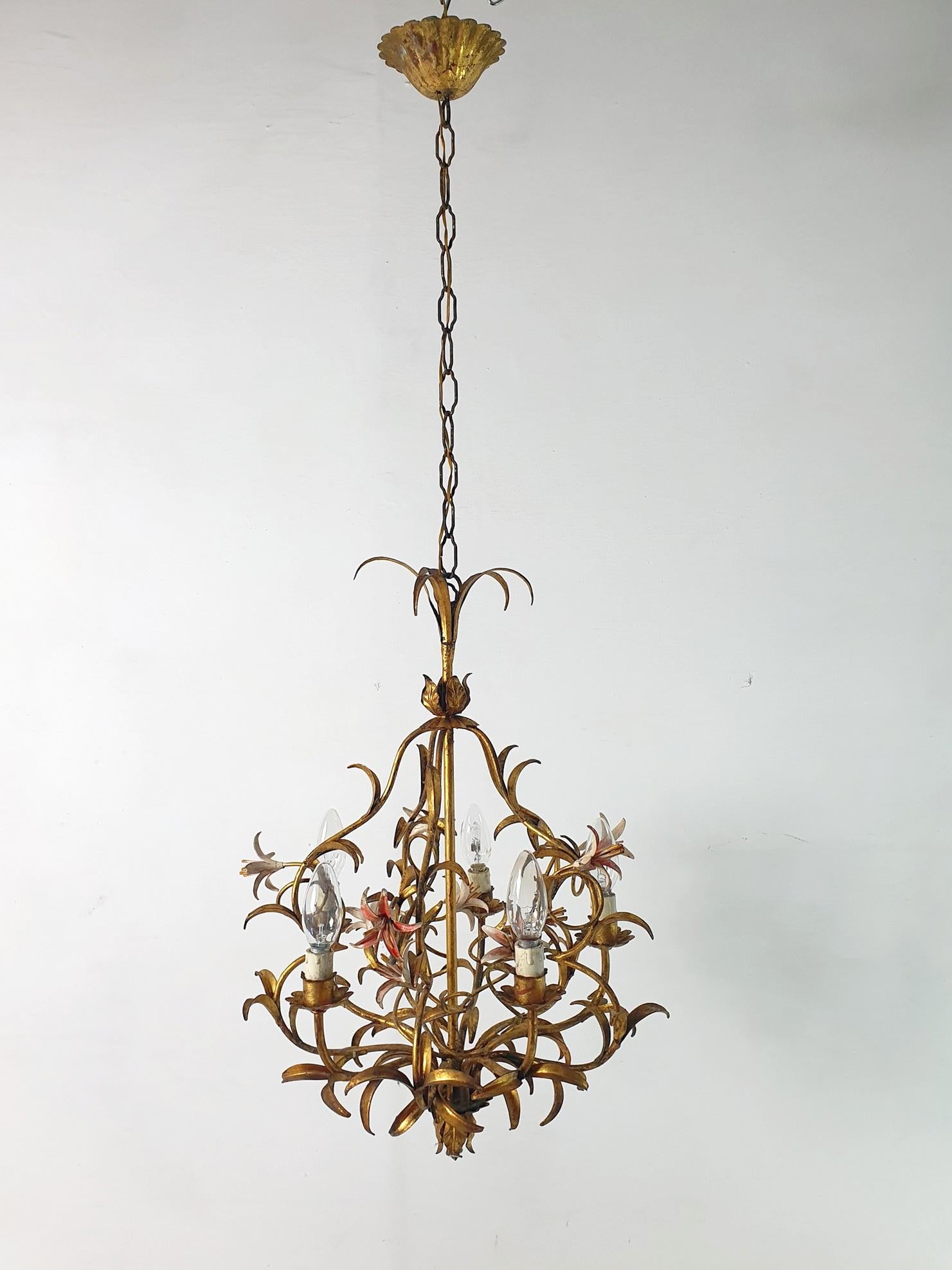 Chandelier from the 1950s in iron and painted with a natural vintage patina. It has six candle lights surrounded with flowers and leaves in different shapes and colors. The lightbulbs used are Edison e14 which are found both in Europe and the United