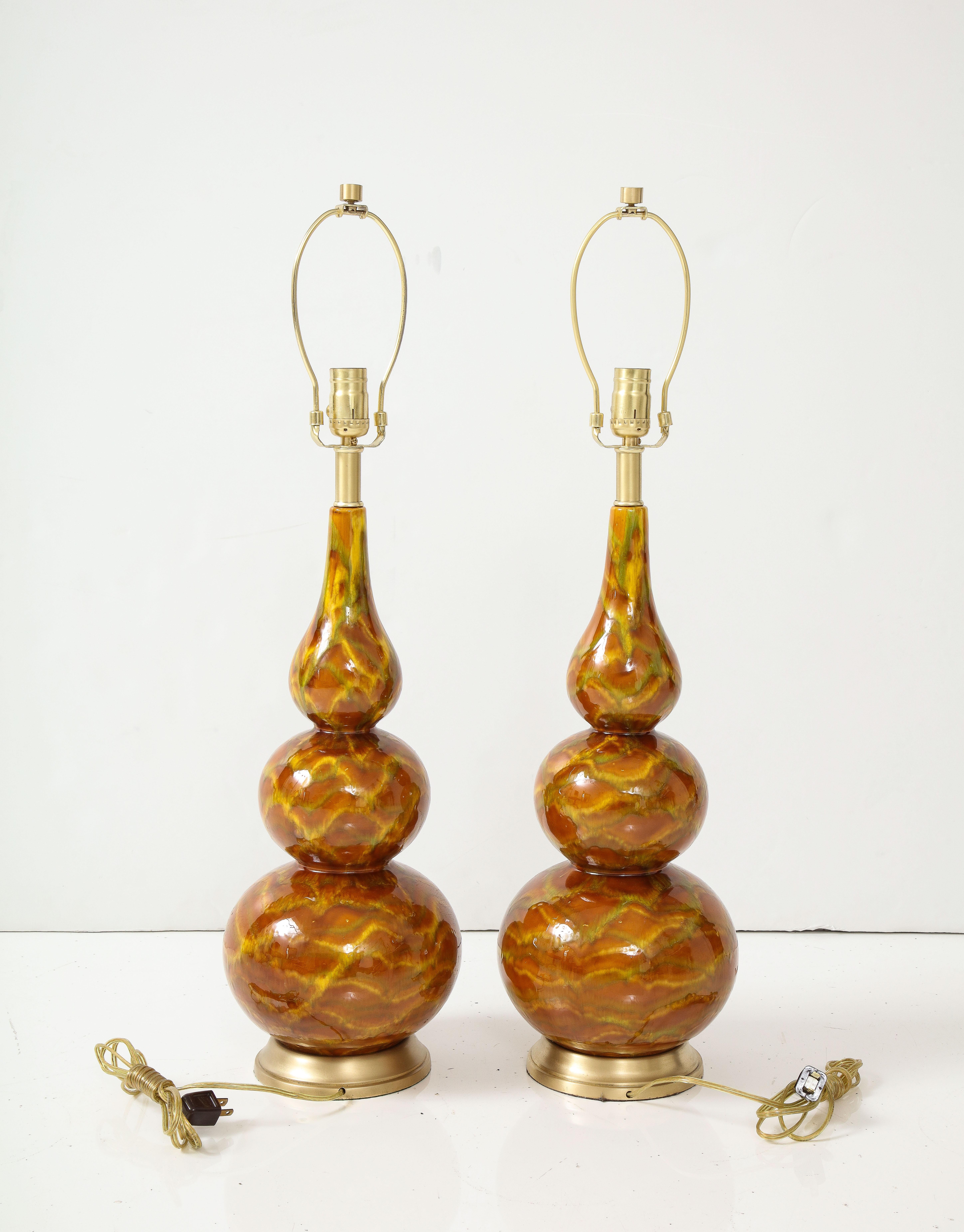 Pair of mottled earth tone glazed ceramic lamps having a sinuous triple gourd shape, sitting on brass bases. Rewired for use in the USA, 100W bulb max.