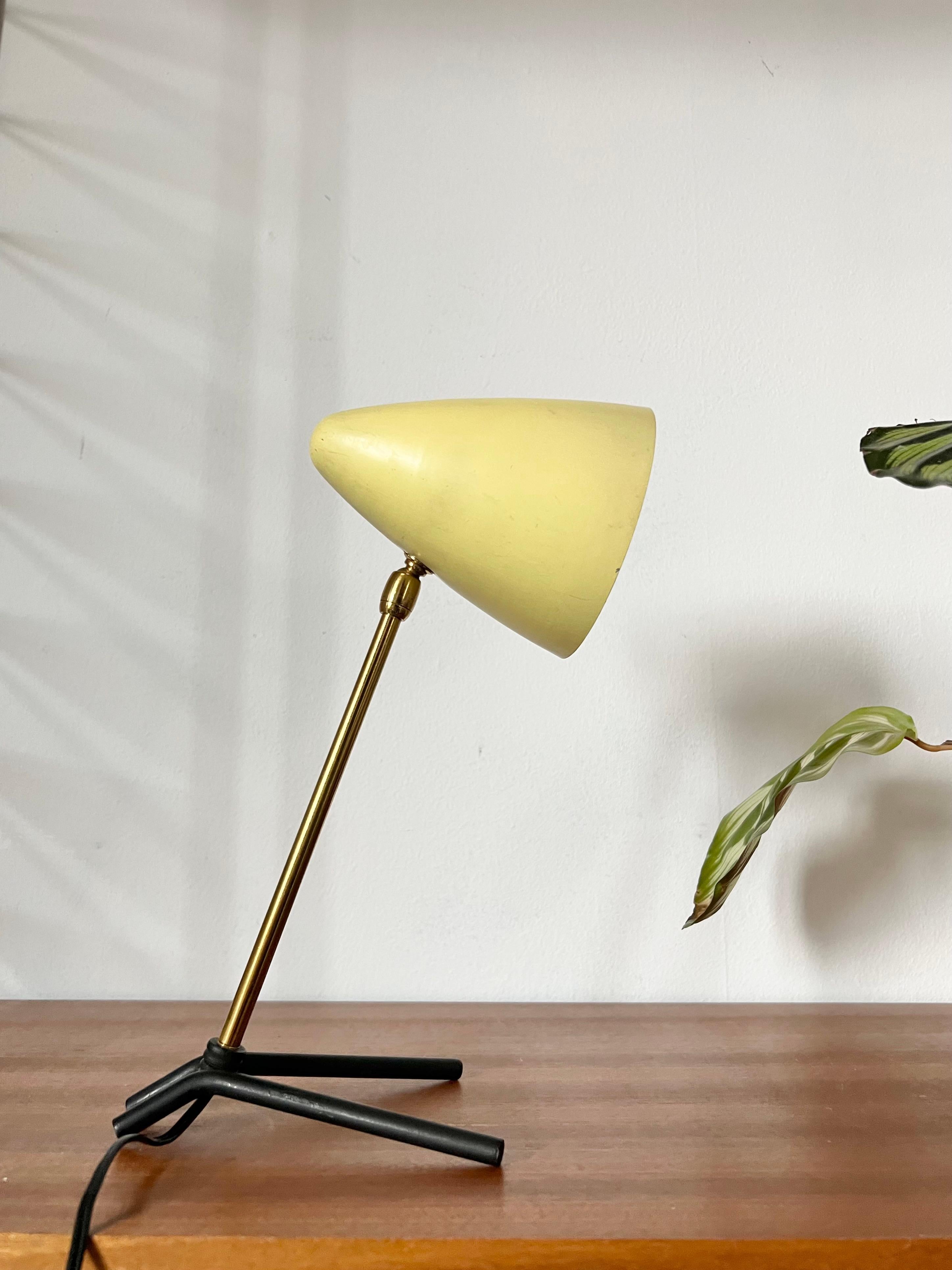 Mid Century Tripod Lampe im Stil von Ostuni.

Produziert in Italien in den 50er Jahren. 

Ein blassgelb lackierter Kegel-Lampenschirm auf einem verstellbaren Messingarm mit schwarz lackierten Bogenfüßen.  
Guter Originalzustand mit einigen