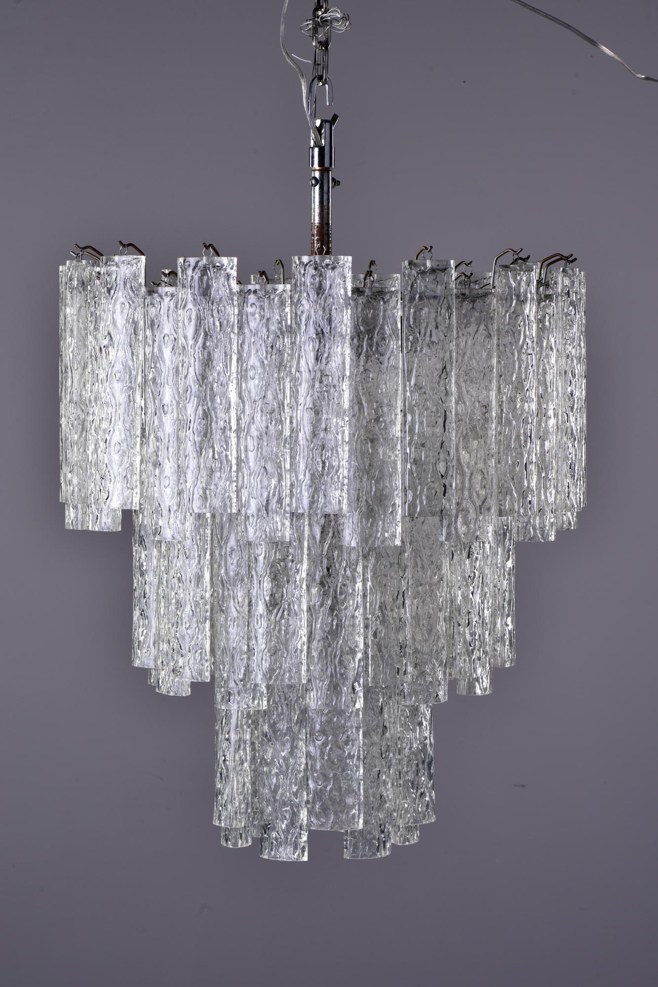 Circa 1960s chandelier with three tiers of clear, textured tronchi glass tubes. Six candelabra sized sockets. New wiring for US electrical standards. Unknown maker.