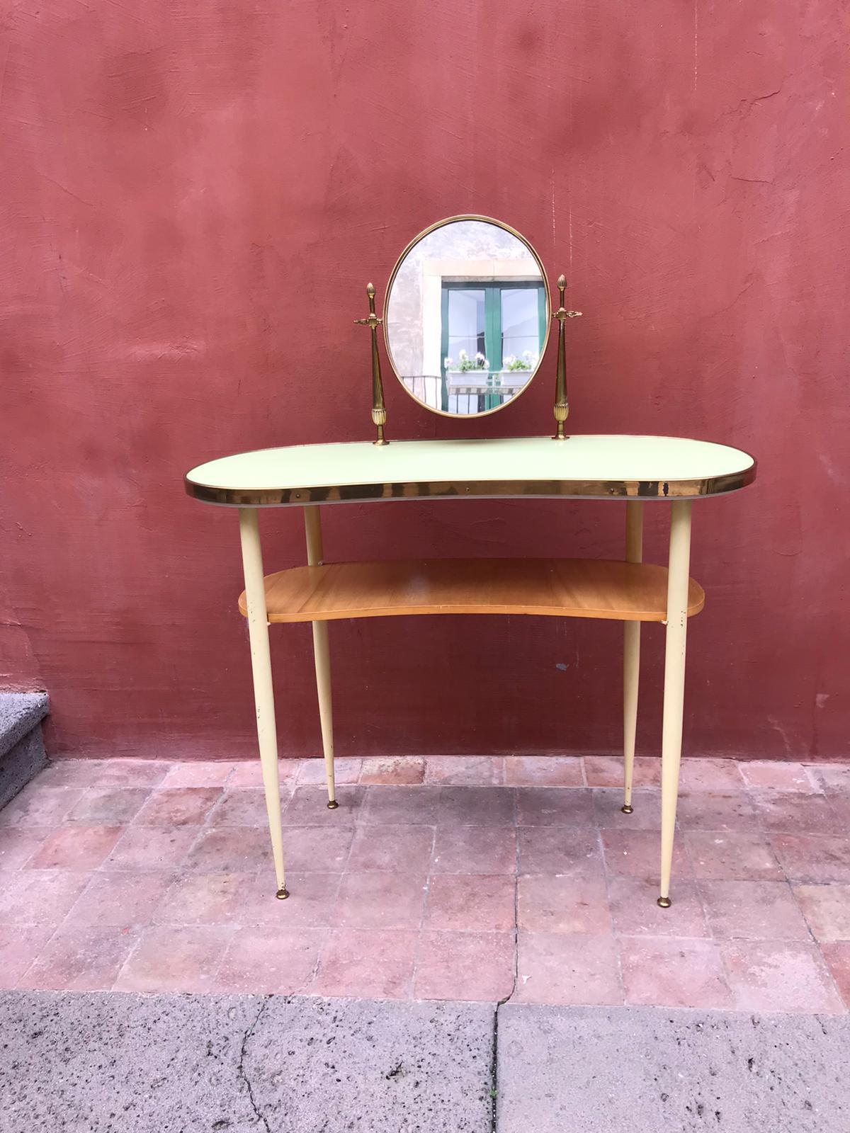 Mid-century vanity table on a four-legged lacquered metal base with a kidney-shaped glass table top and one
wooden shelf. The oval mirror is tilt able.
Good vintage condition.