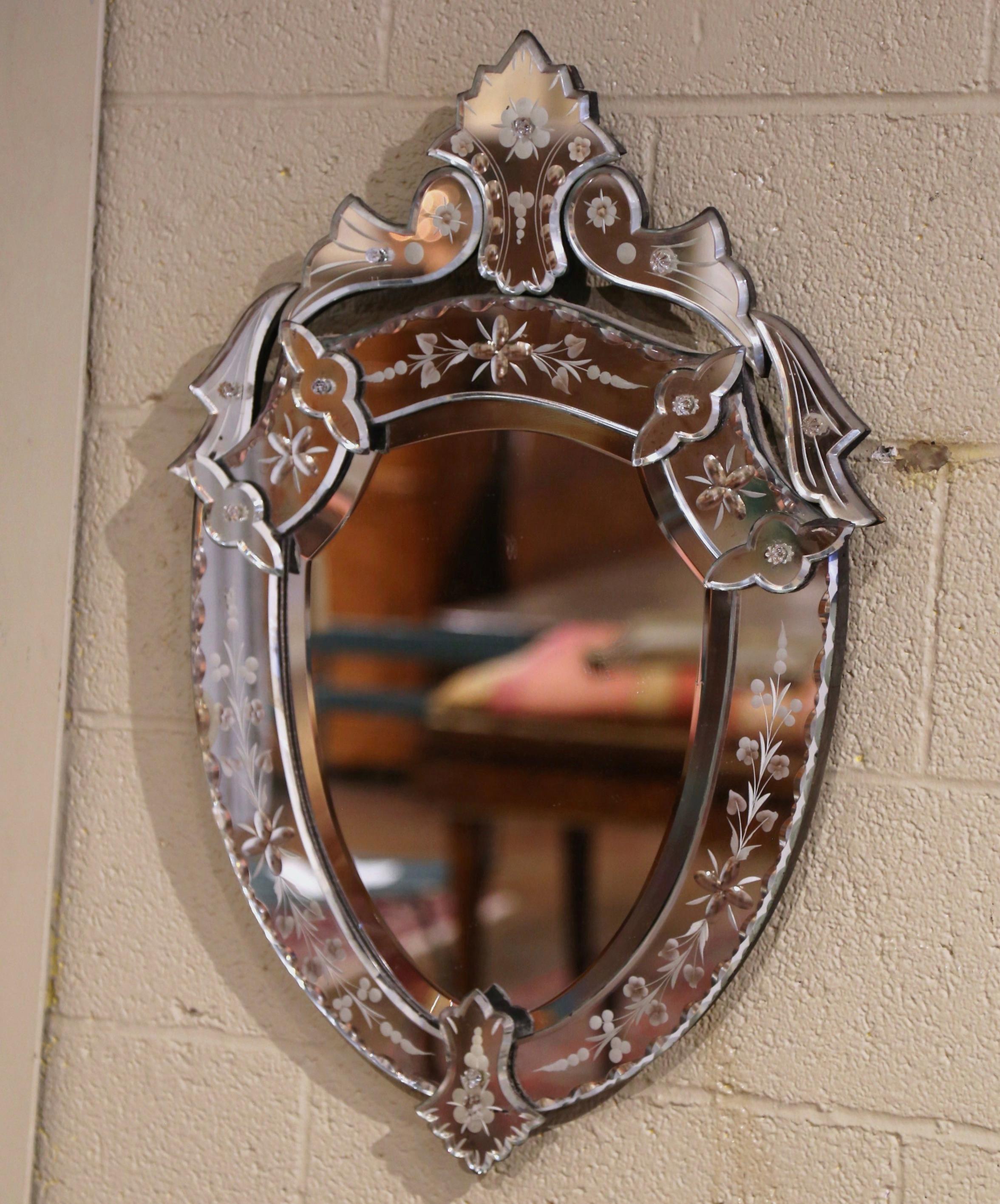 Dekorieren Sie ein Badezimmer oder ein Schlafzimmer mit diesem eleganten, antiken Spiegel. Der um 1960 in Venedig (Italien) gefertigte Wandspiegel in Form eines Schildes mit geschnitztem Dekor am Giebel weist eine handgemalte florale Ätzung zwischen