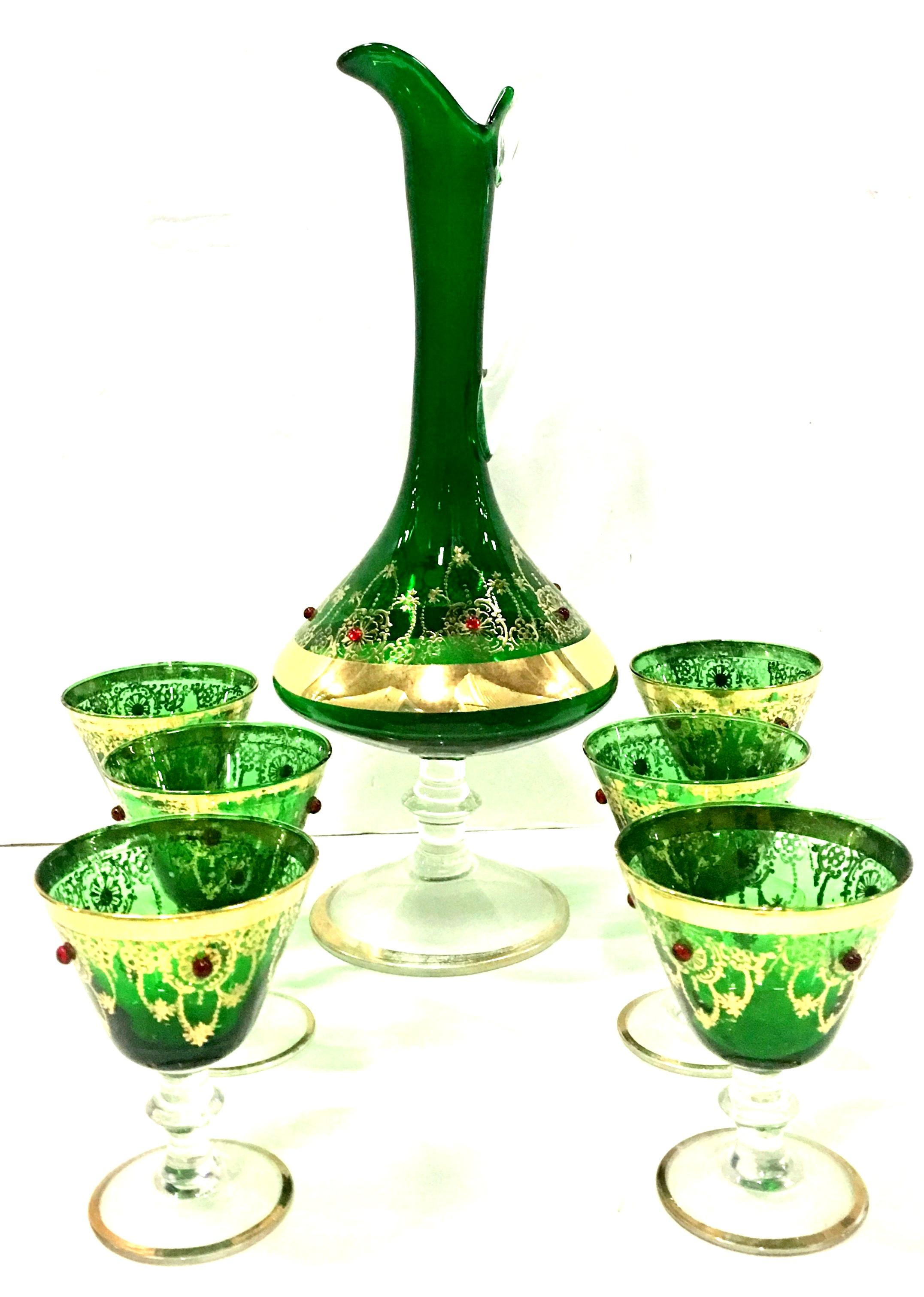 Mid-Century Italian 22 karat Gold & Emerald Green Venetian Glass Drinks Set Of Seven Pieces. This hand-painted seven piece set features a spouted and applied handled footed pitcher and six cordial footed stem glasses. The 22 karat gold scroll and
