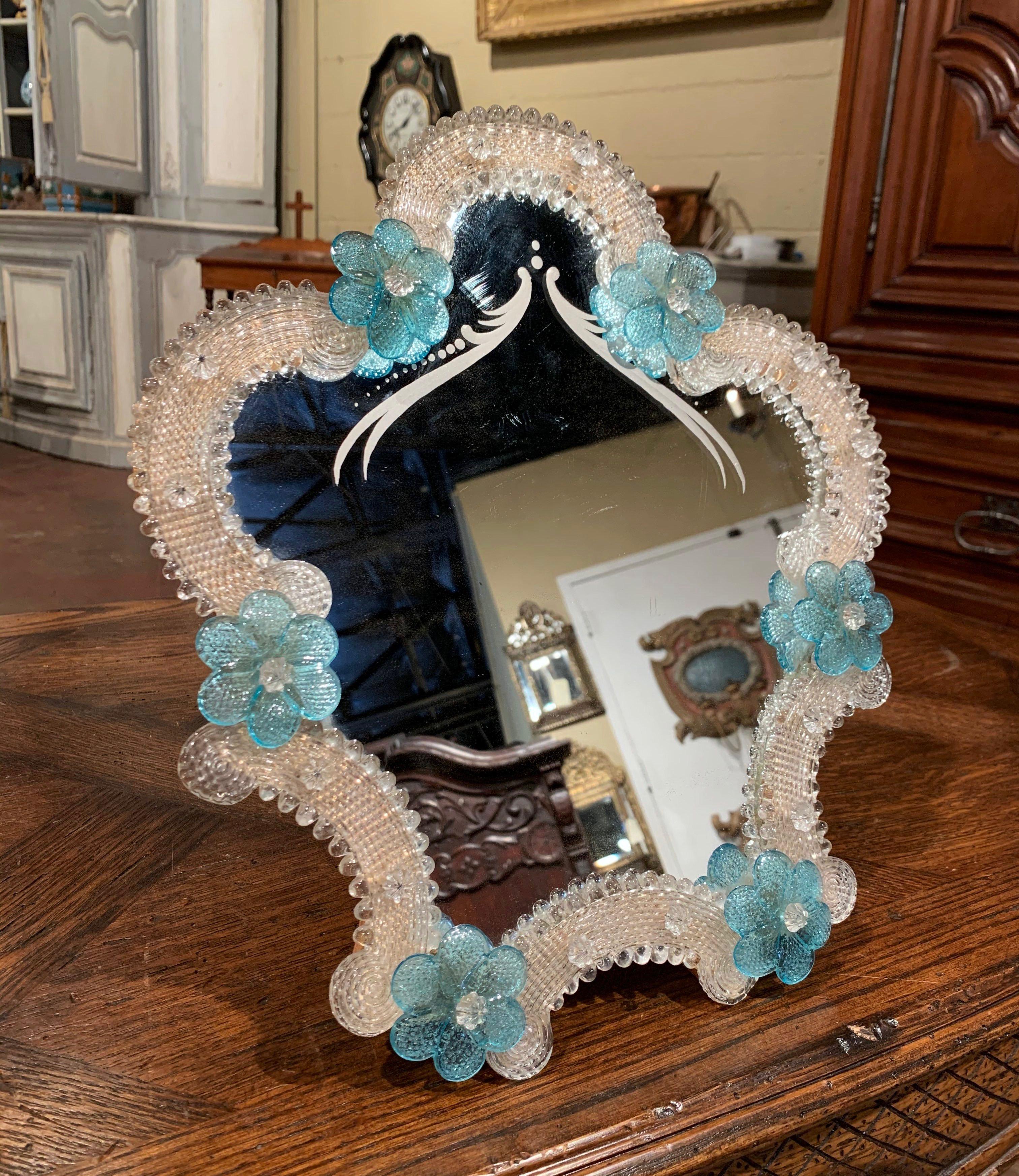 This elegant table mirror was created in Murano, Italy circa 1960, the free standing vanity mirror with wooden back is surrounded with handmade clear and light blue Bohemian flowers. The decorative mirror is in excellent condition and further