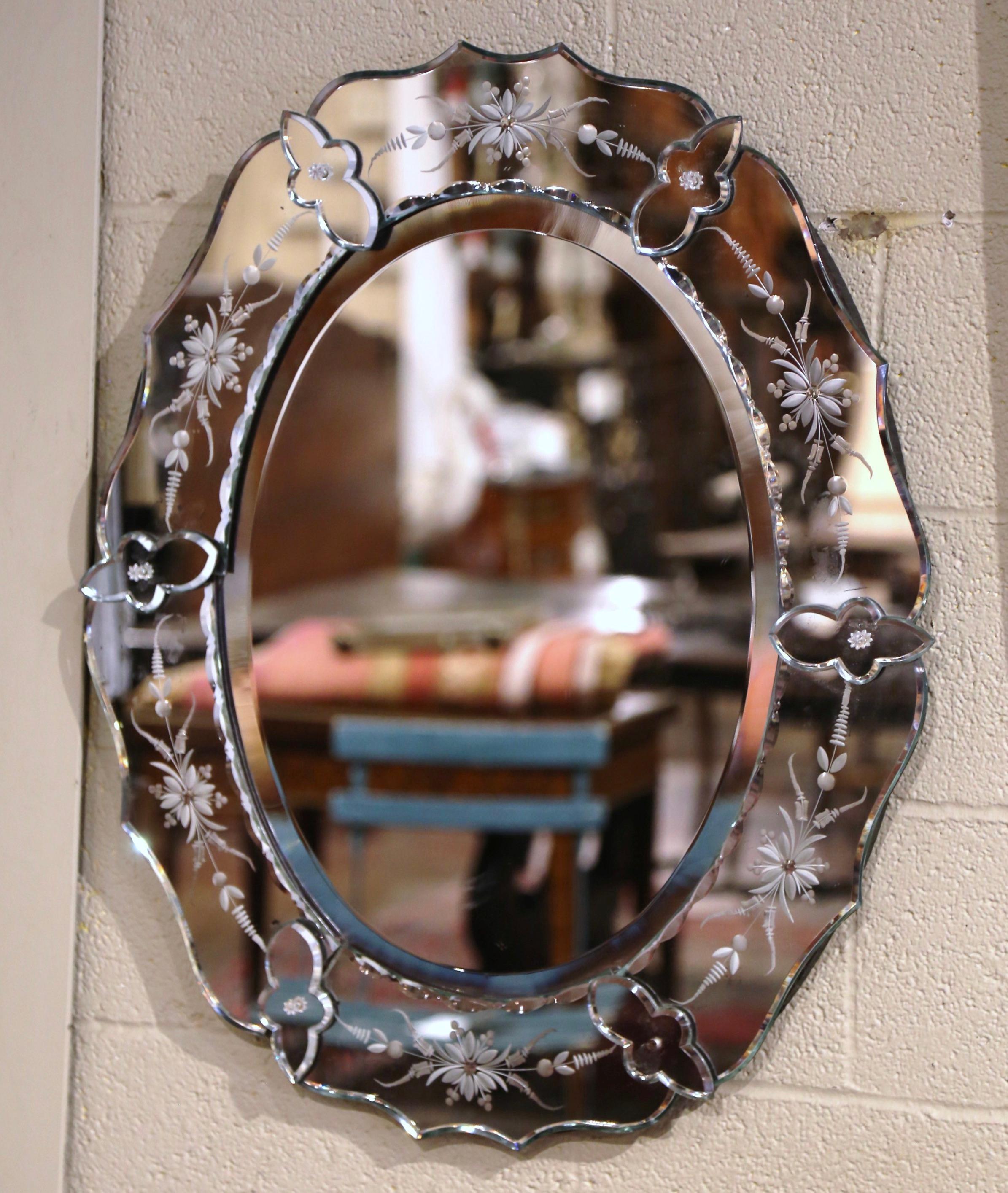 Decorate a powder room or a bedroom with this elegant, antique Venetian mirror. Crafted in Italy, circa 1960 and oval in shape with scalloped edges, the wall mirror features hand painted floral etching between raised medallions embellished by