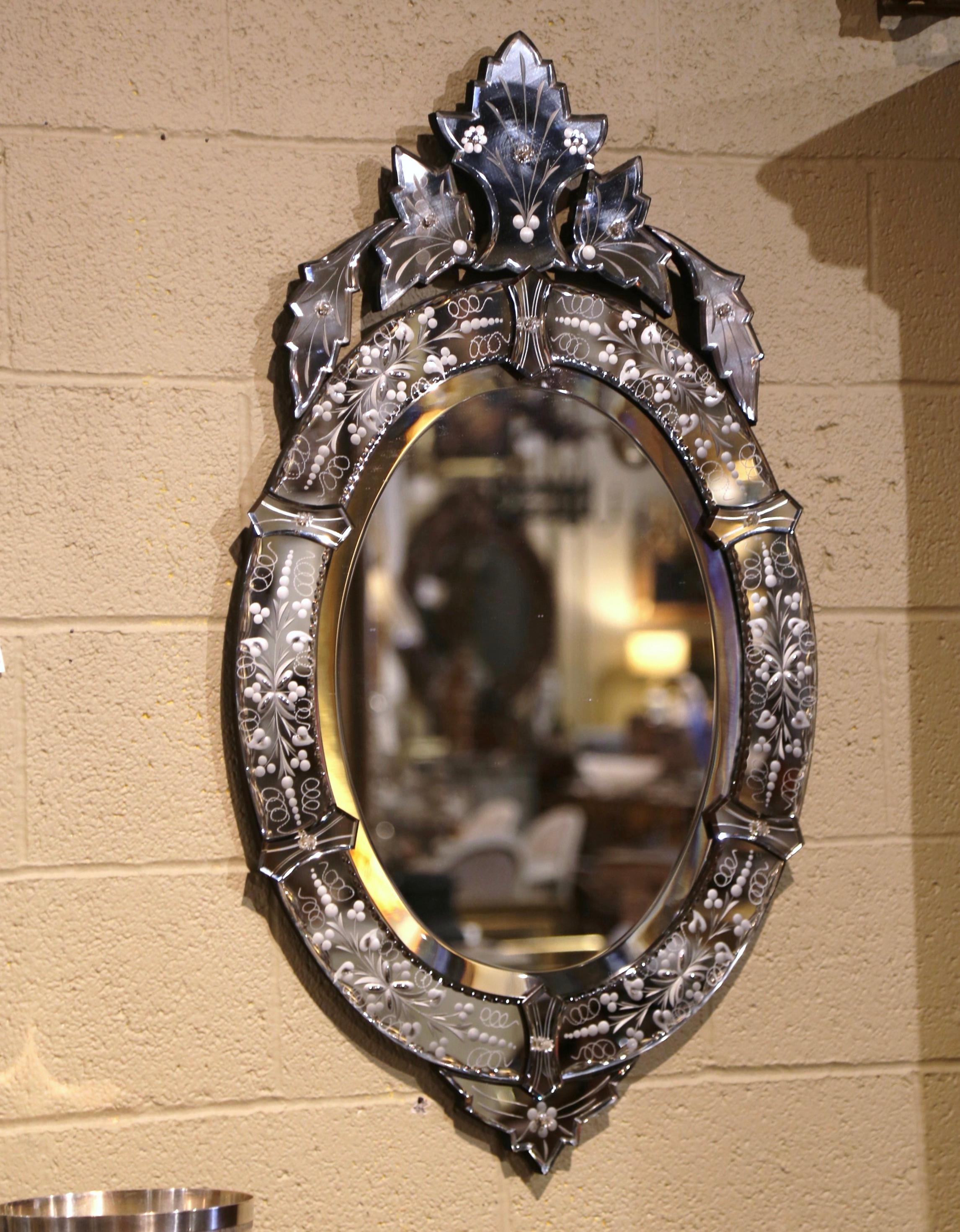 Arreda una toilette o una camera da letto con questo elegante specchio. Realizzato a Venezia, Italia, intorno al 1960 e di forma ovale, lo specchio da parete presenta un motivo a conchiglia intagliato sul frontone con fogliame e rosette floreali su