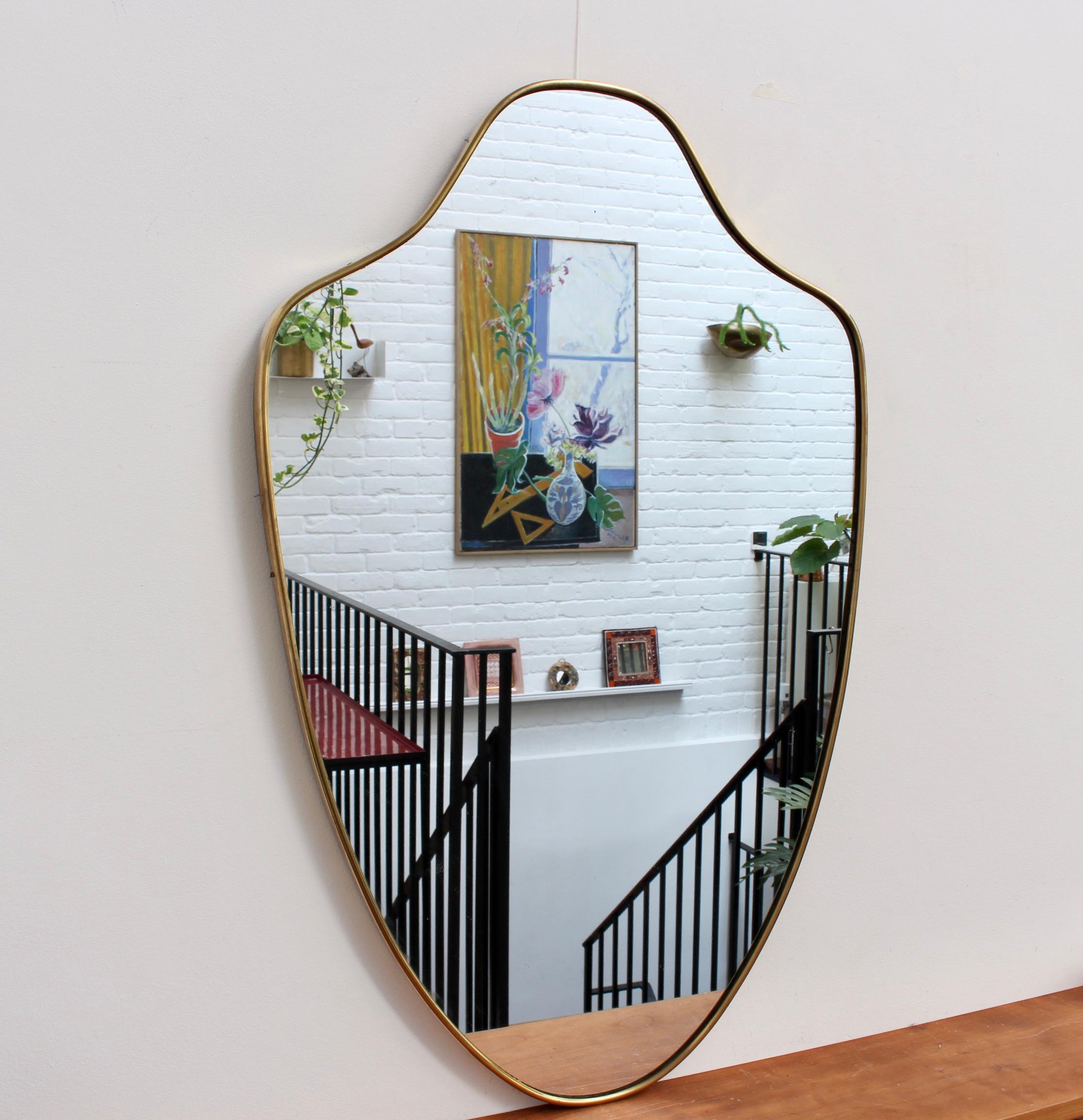 Midcentury Italian wall mirror with brass frame, (1950s). This mirror is simply elegant and characterful in a modern Gio Ponti style. The piece is in overall good condition with a characterful, aged patina on the frame. Please see the many photos